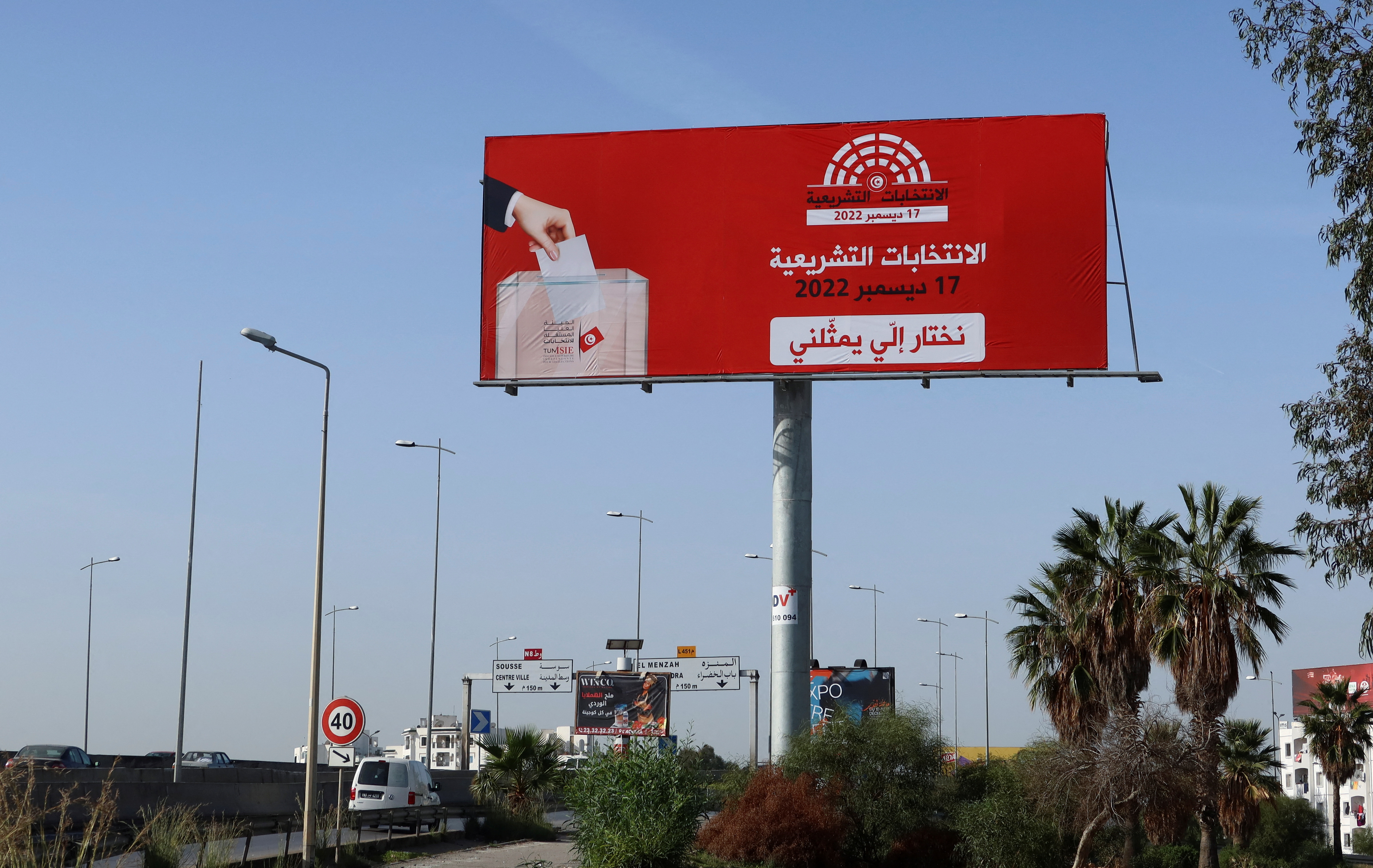 Vehicles drive past a campaign billboard for the upcoming parliamentary election in Tunis