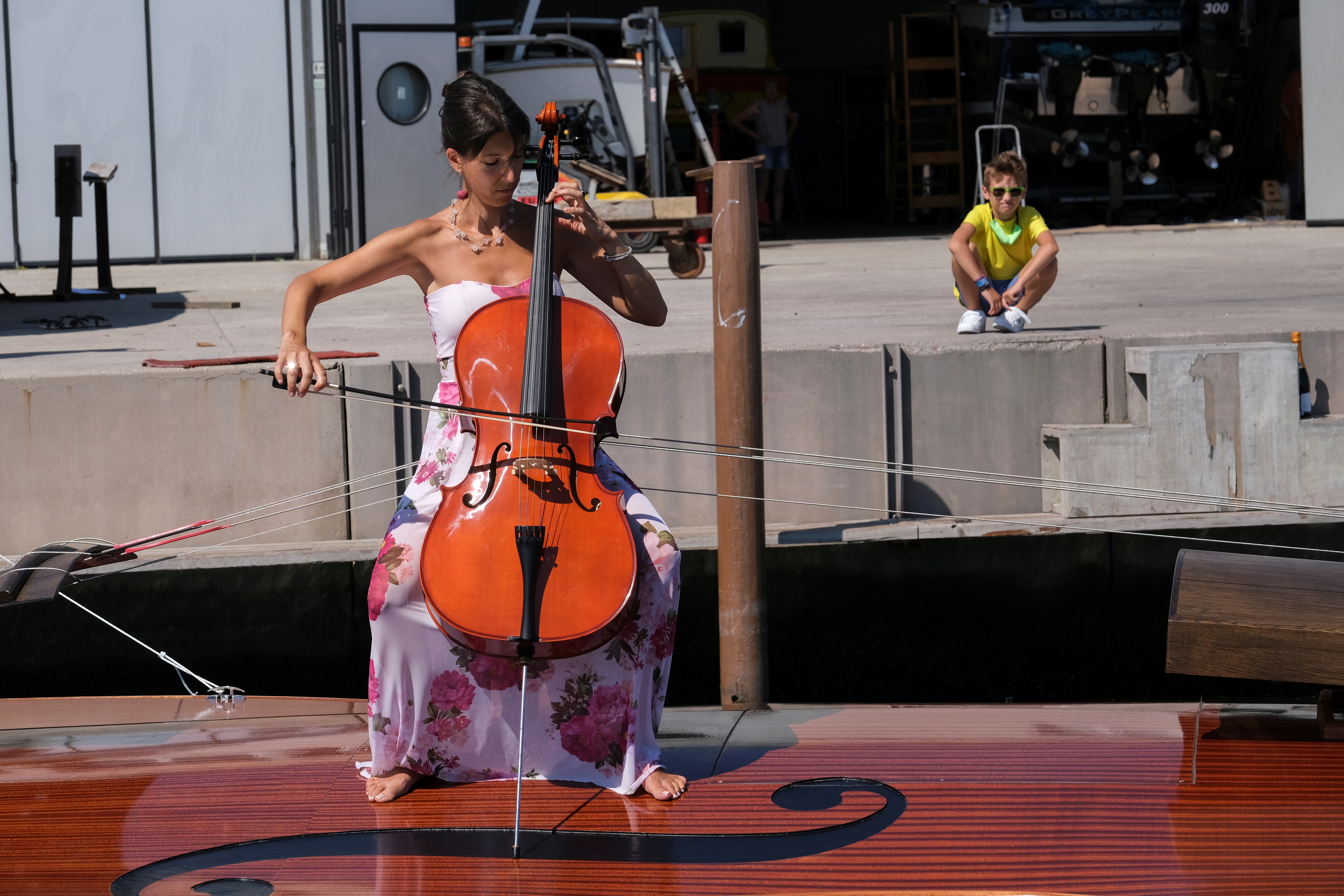 A musician plays a cello onboard a boat in the shape of a violin, titled 'Violin of Noah', during a test-ride, in Venice