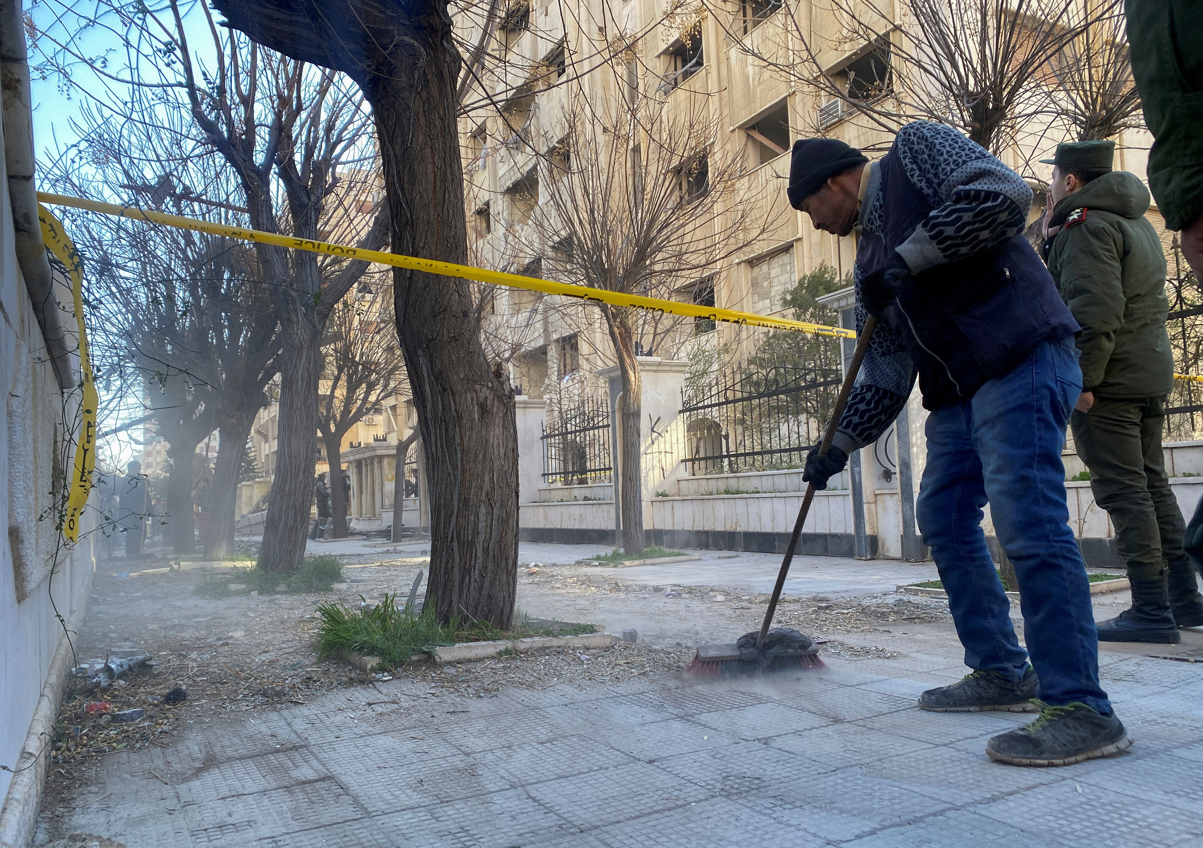 A man sweeps the street near the site of a rocket attack, in central Damascus' Kafr Sousa neighborhood