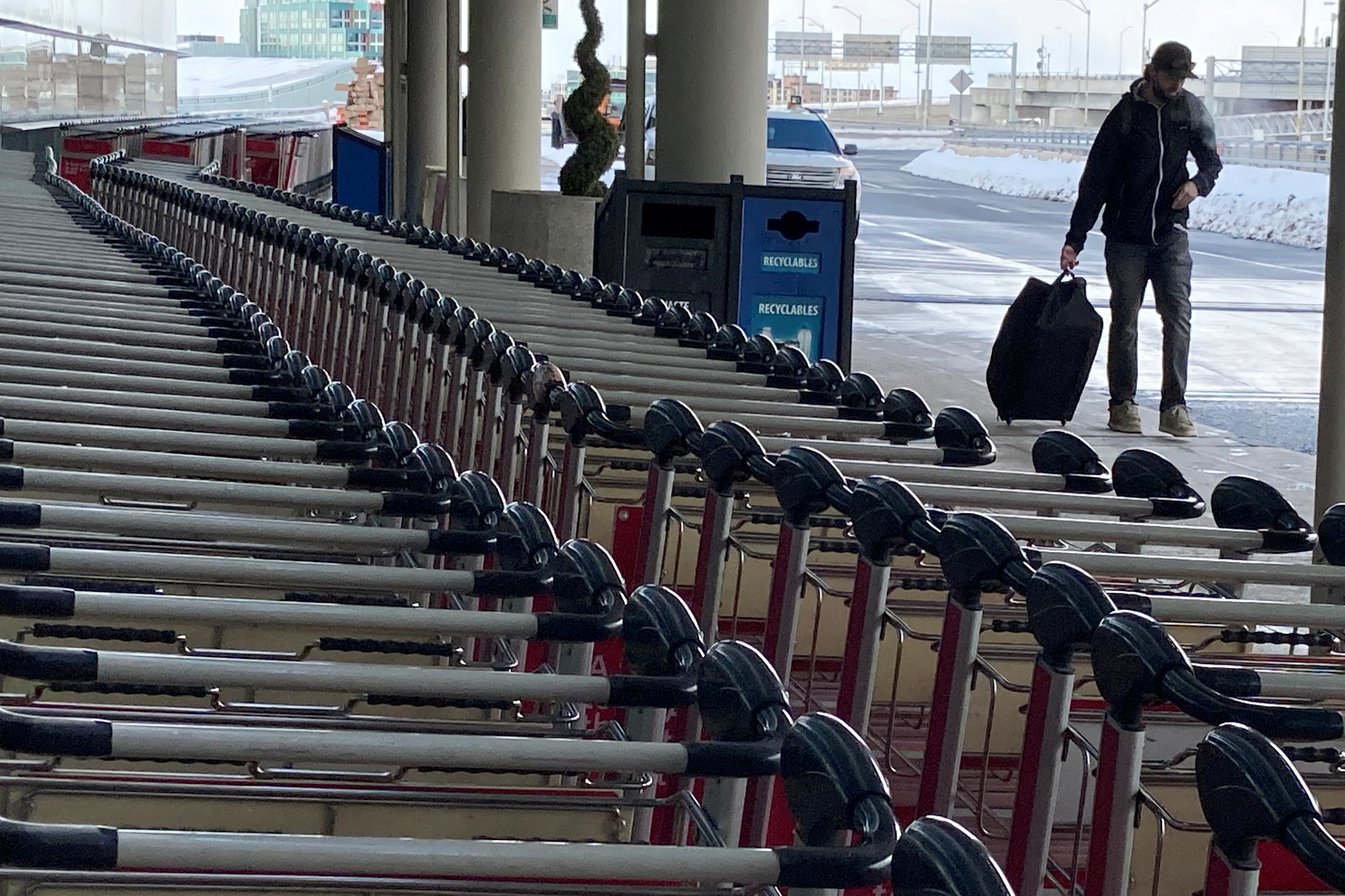 A man pulls his luggage past baggage carts at Toronto Pearson International Airport in Mississauga