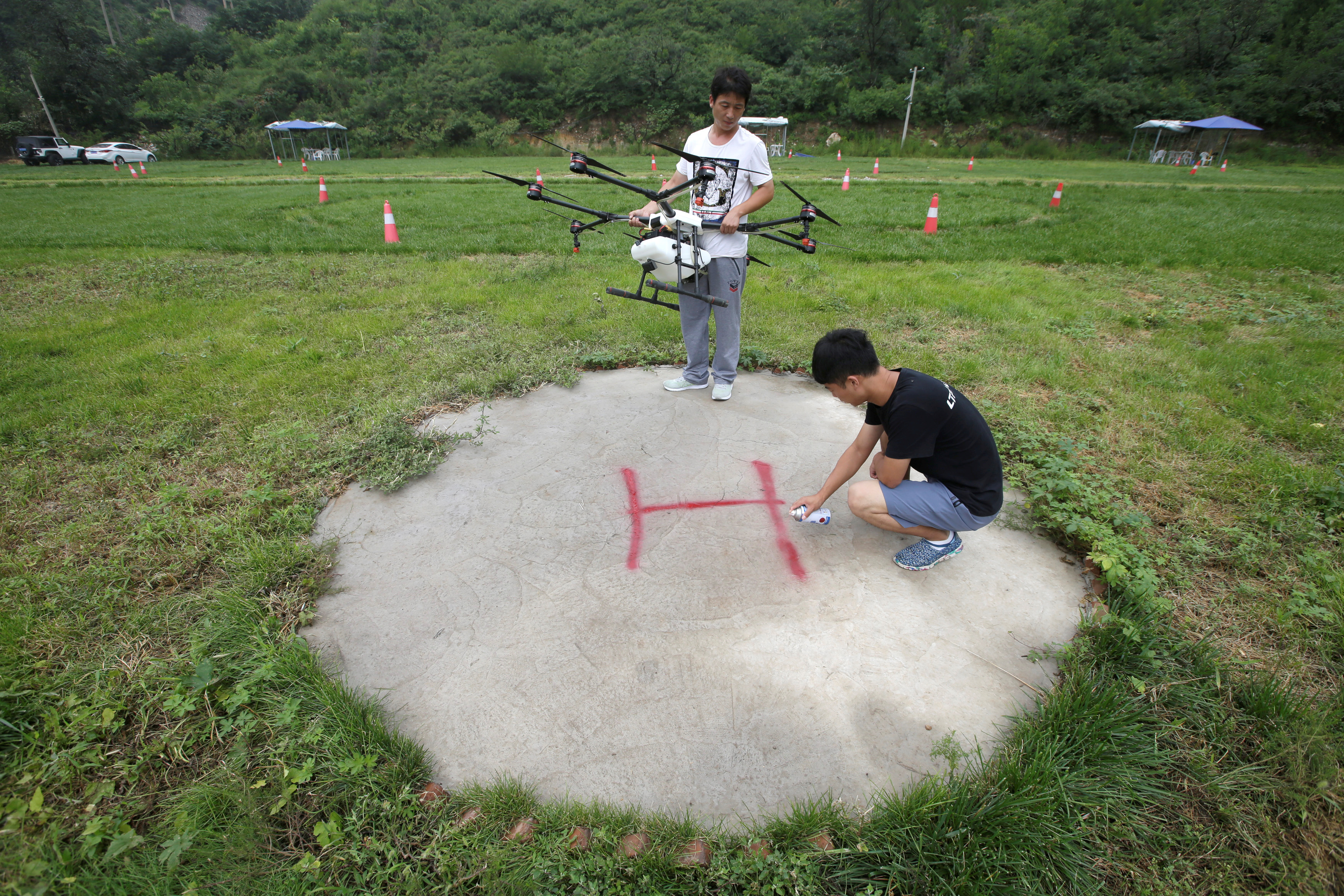 An instructor sets up landing sign as a trainee prepares to learn to fly an aerosol drone at LTFY drone training school on the outskirts of Beijing