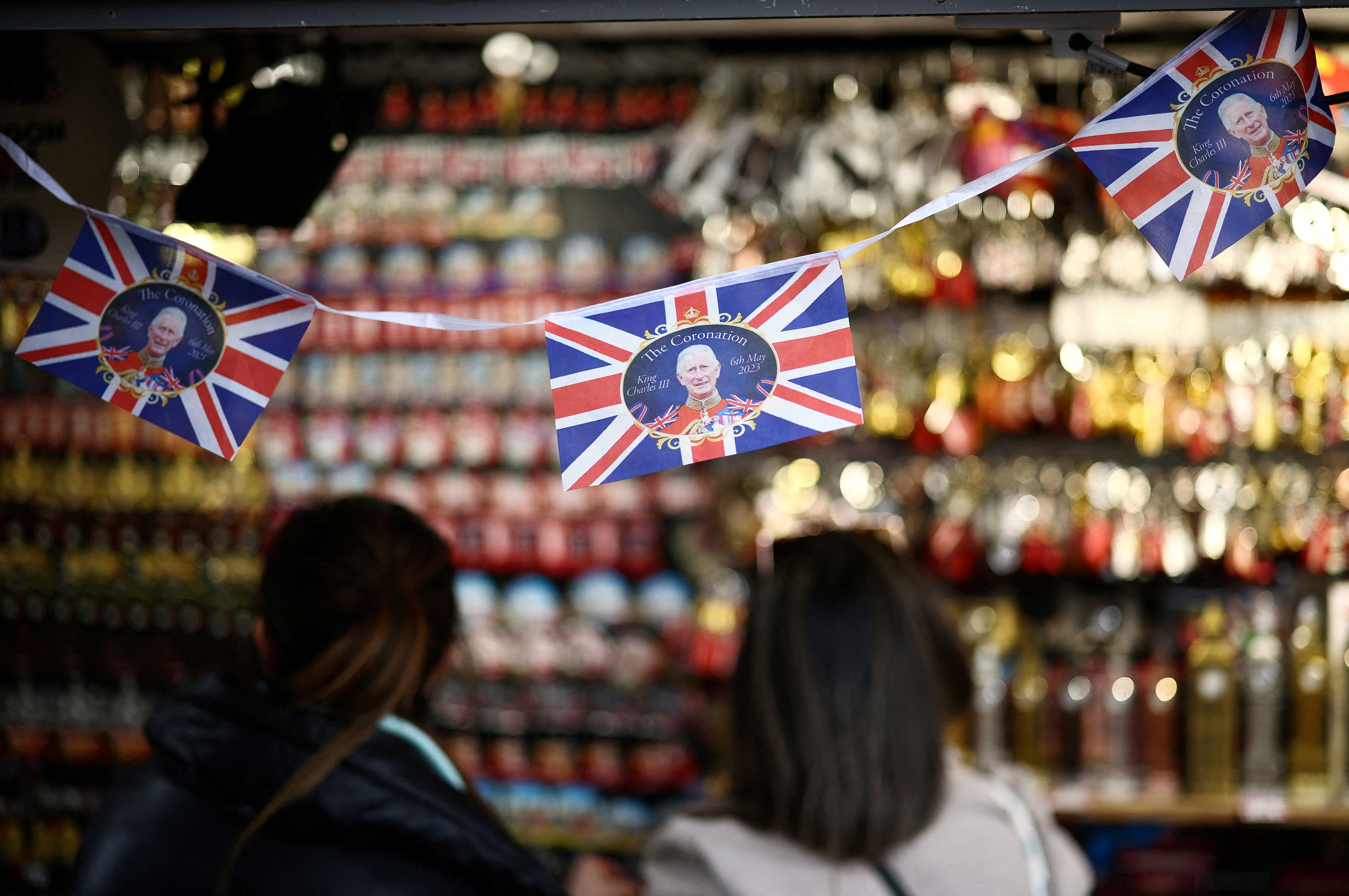 People browse a souvenir kiosk that is displaying items designed for the Coronation of King Charles III in London
