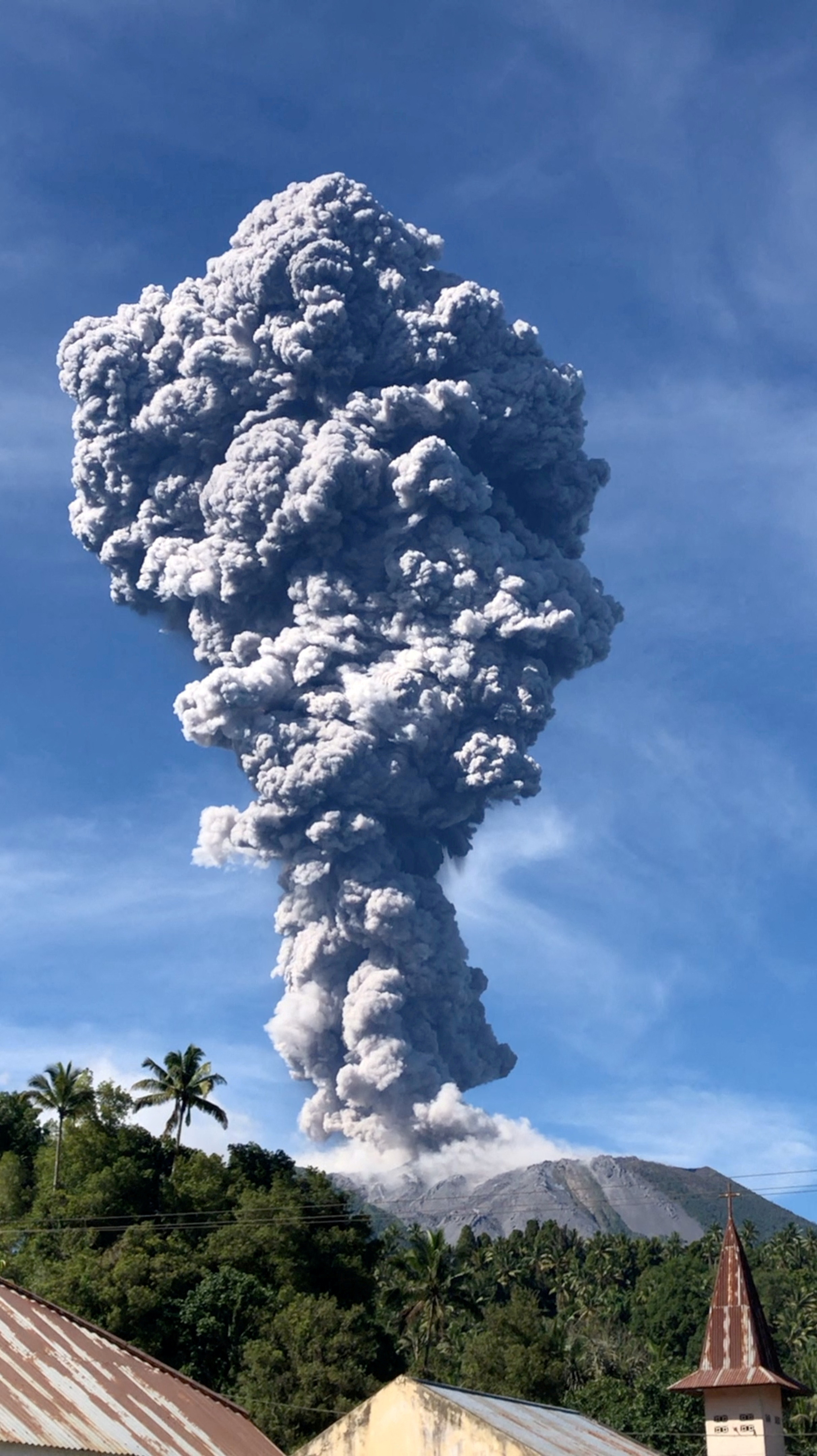A column of ash rises over the Gunung Ibu volcano