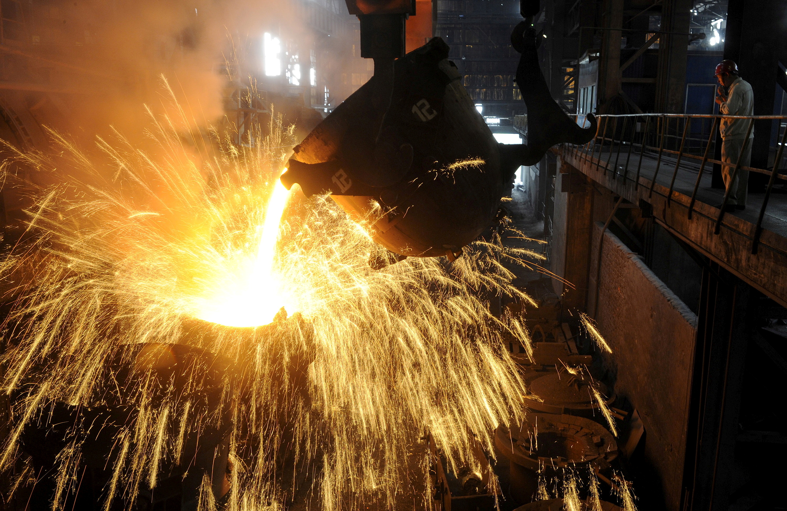 An employee monitors molten iron being poured into a container at a steel plant in Hefei