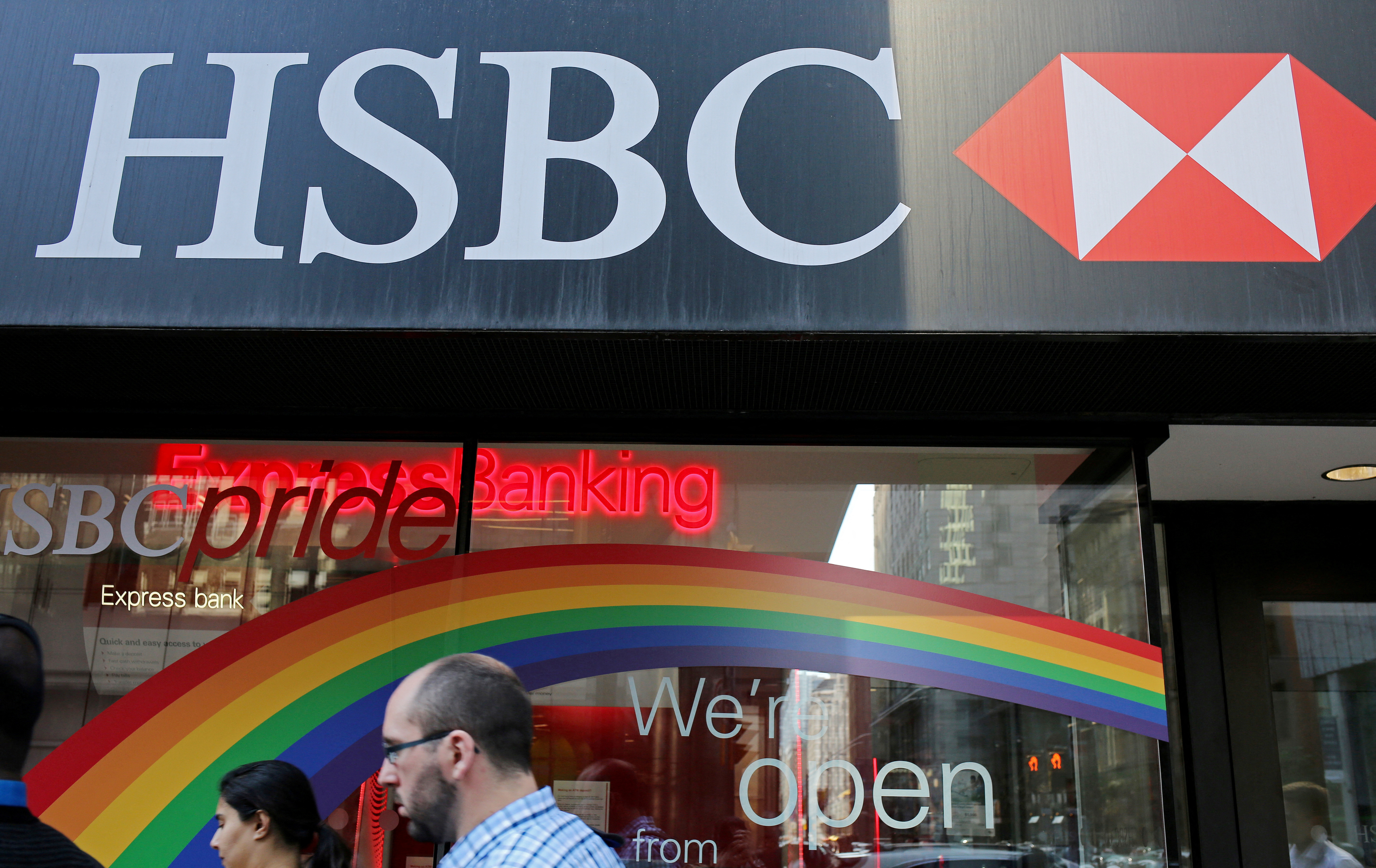 People pass by a branch of HSBC bank adorned with colours of the Pride rainbow flag, in downtown Toronto