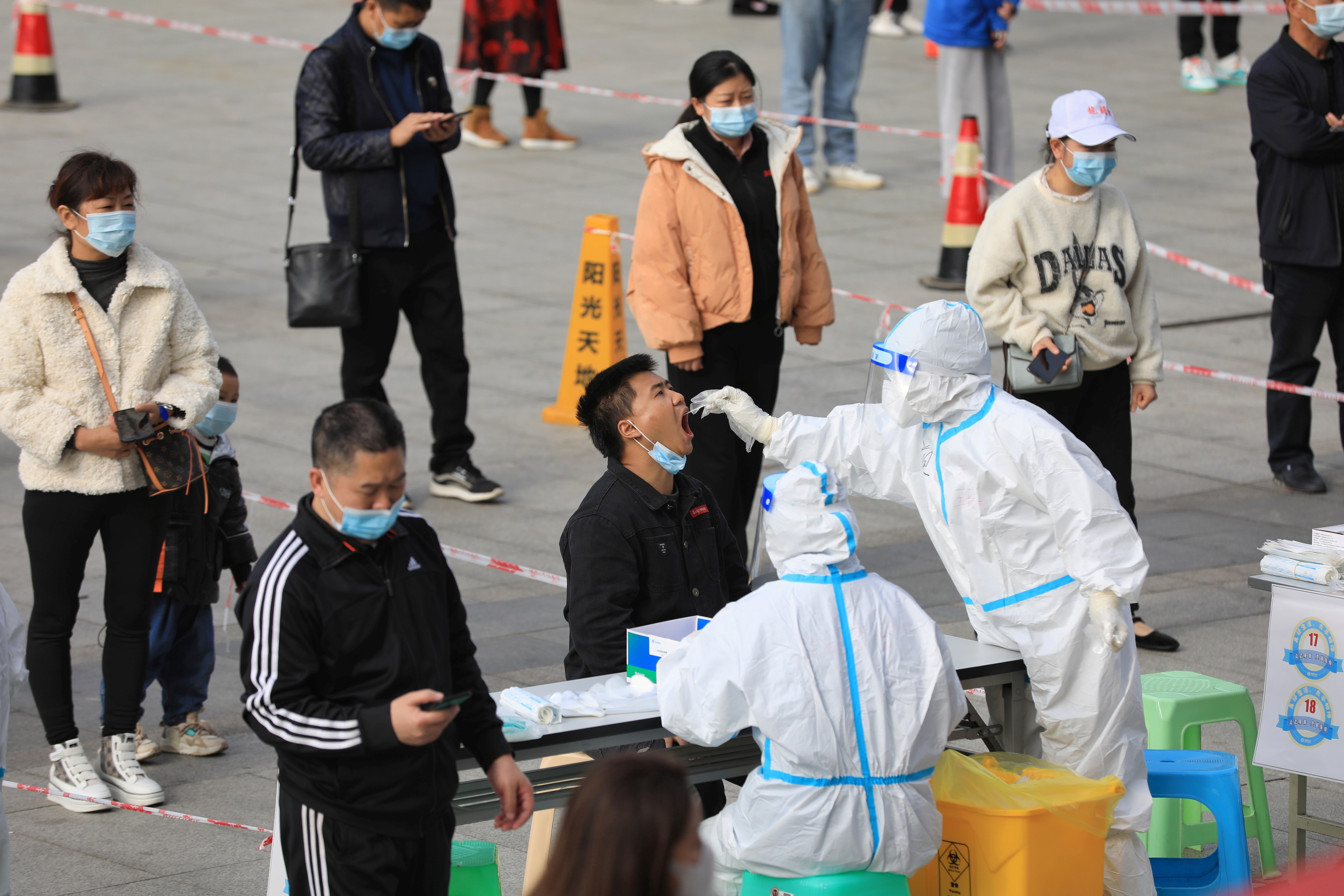 A medical worker in protective suit collects a swab from a man during a mass nucleic acid testing in Huichuan district following new cases of the coronavirus disease (COVID-19) in Zunyi, Guizhou province, China October 23, 2021. cnsphoto via REUTERS   
