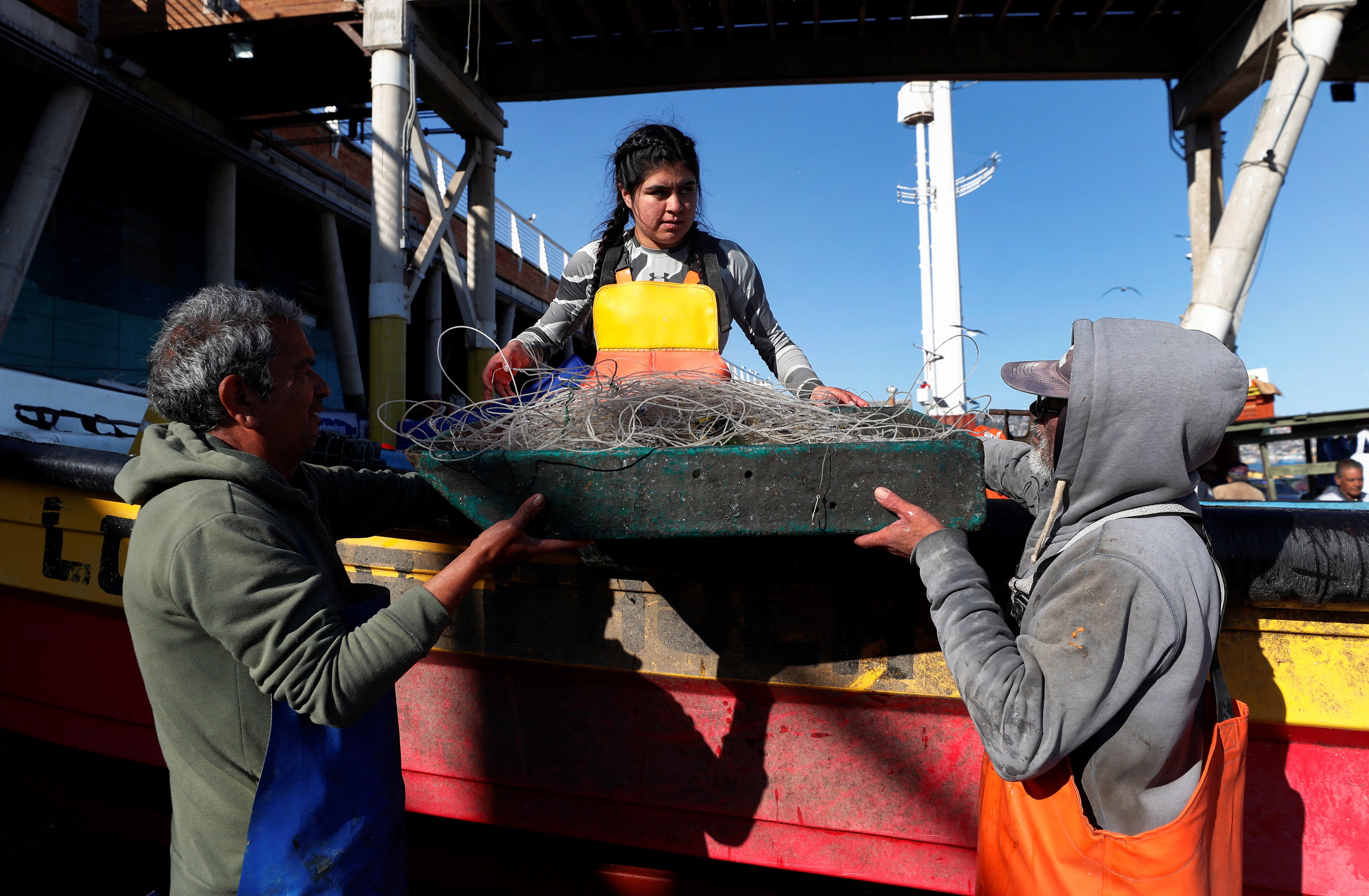 Artisanal fishers hold a box with an empty fishing net, after arriving at a fishermen's cove in Valparaiso
