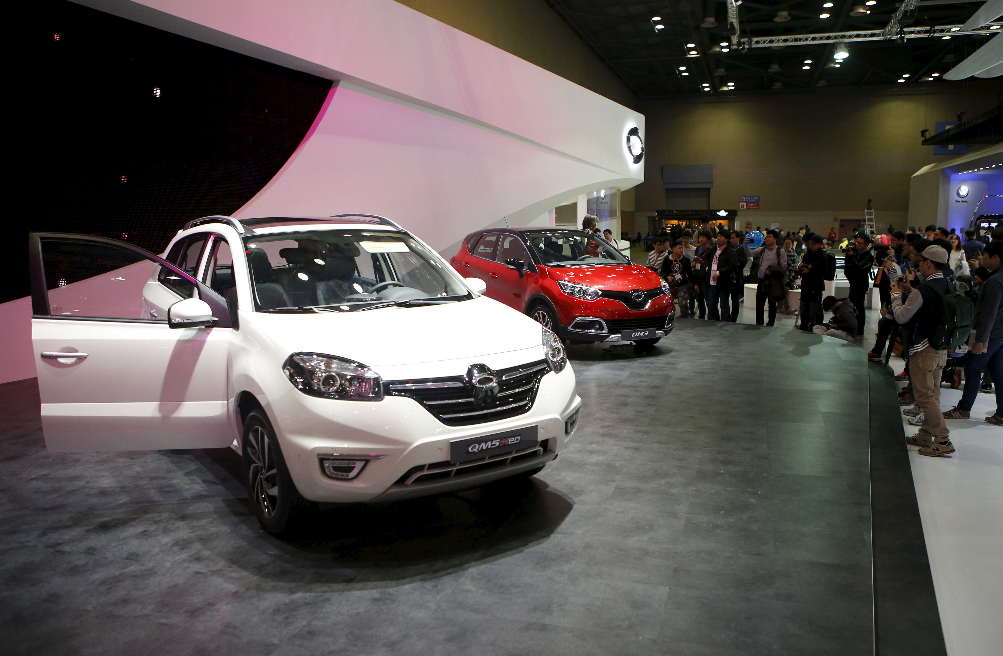 Renault Samsung QM5 is seen as visitors and photographers gather to take photographs of a model posing next to a Renault Samsung QM3 at the Seoul Motor Show 2015
