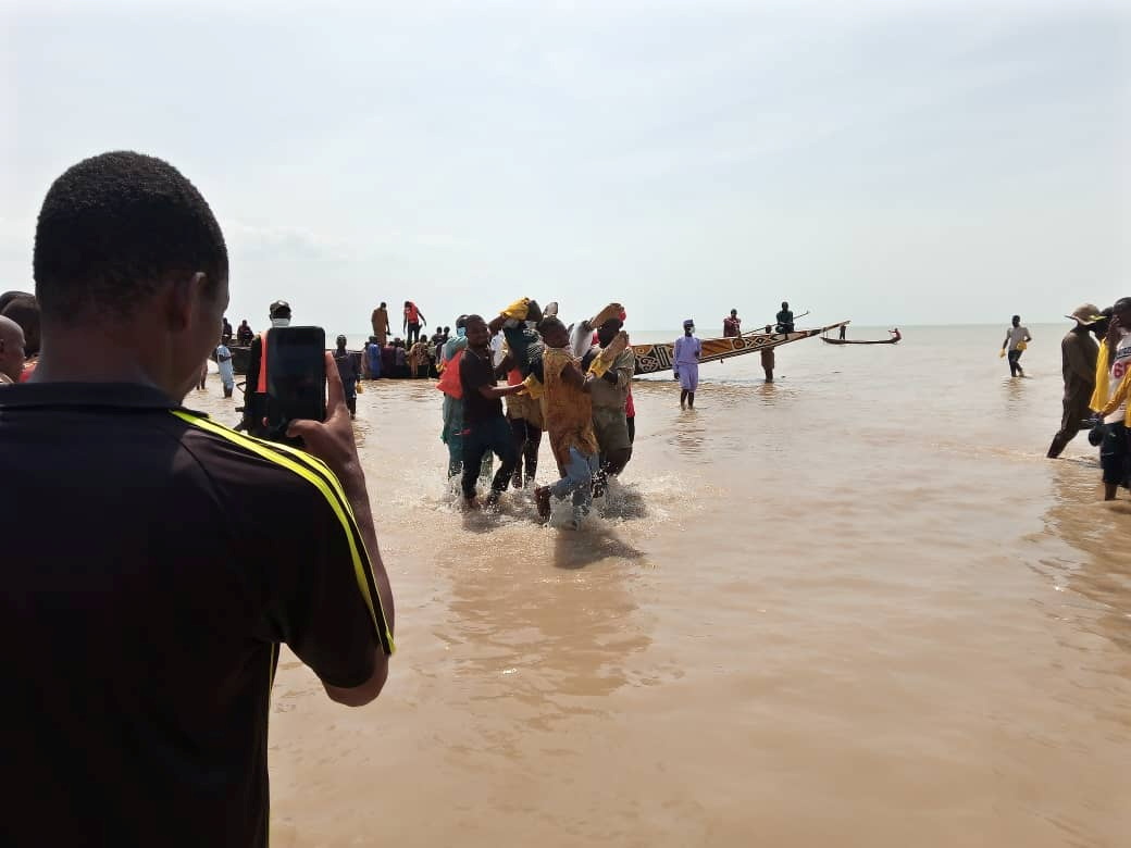 A man takes a picture as the body of one of the victims of a boat accident is being retrieved from the boat in Kebbi