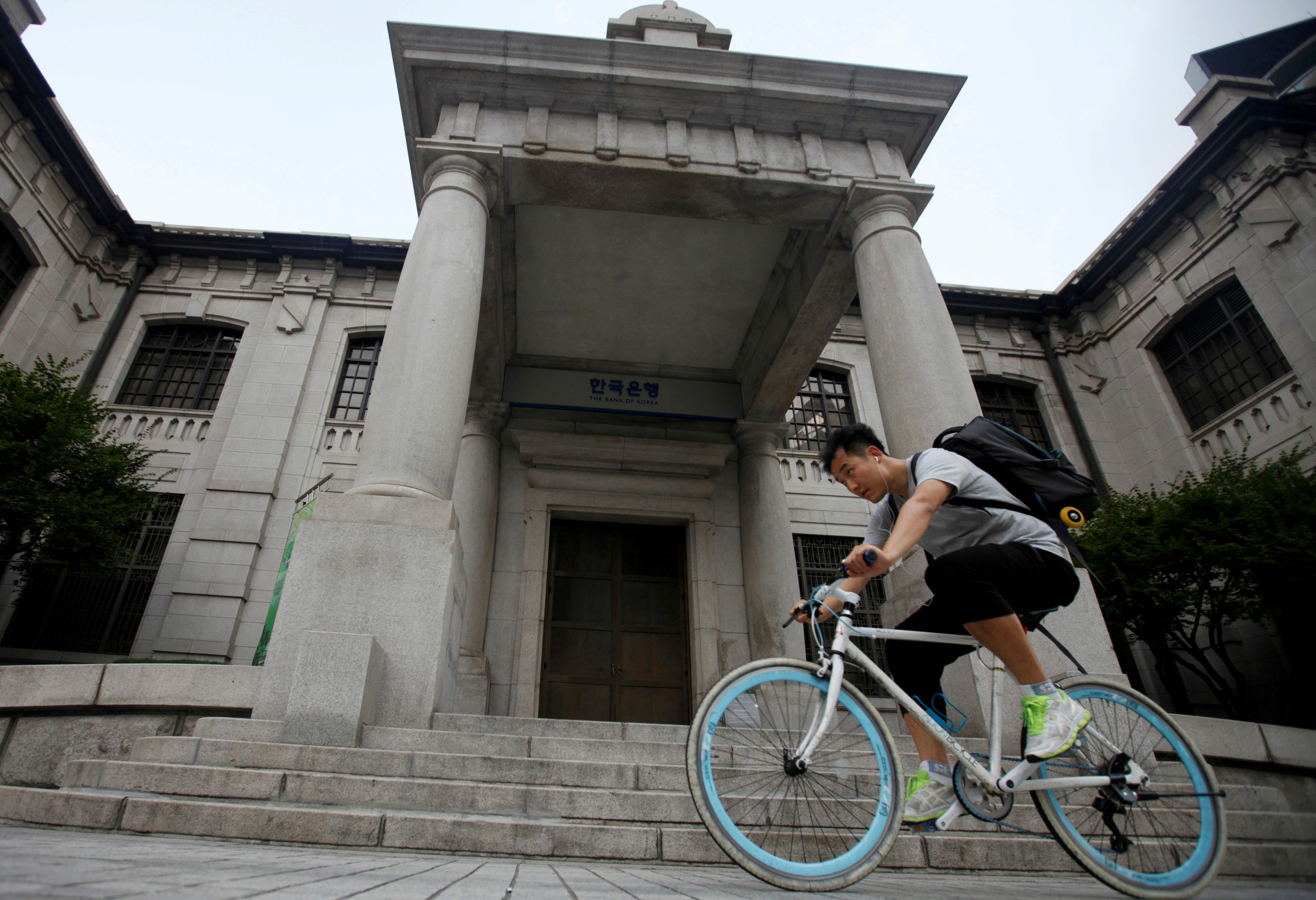 A man gets on a bicycle in front of the Bank of Korea in Seoul