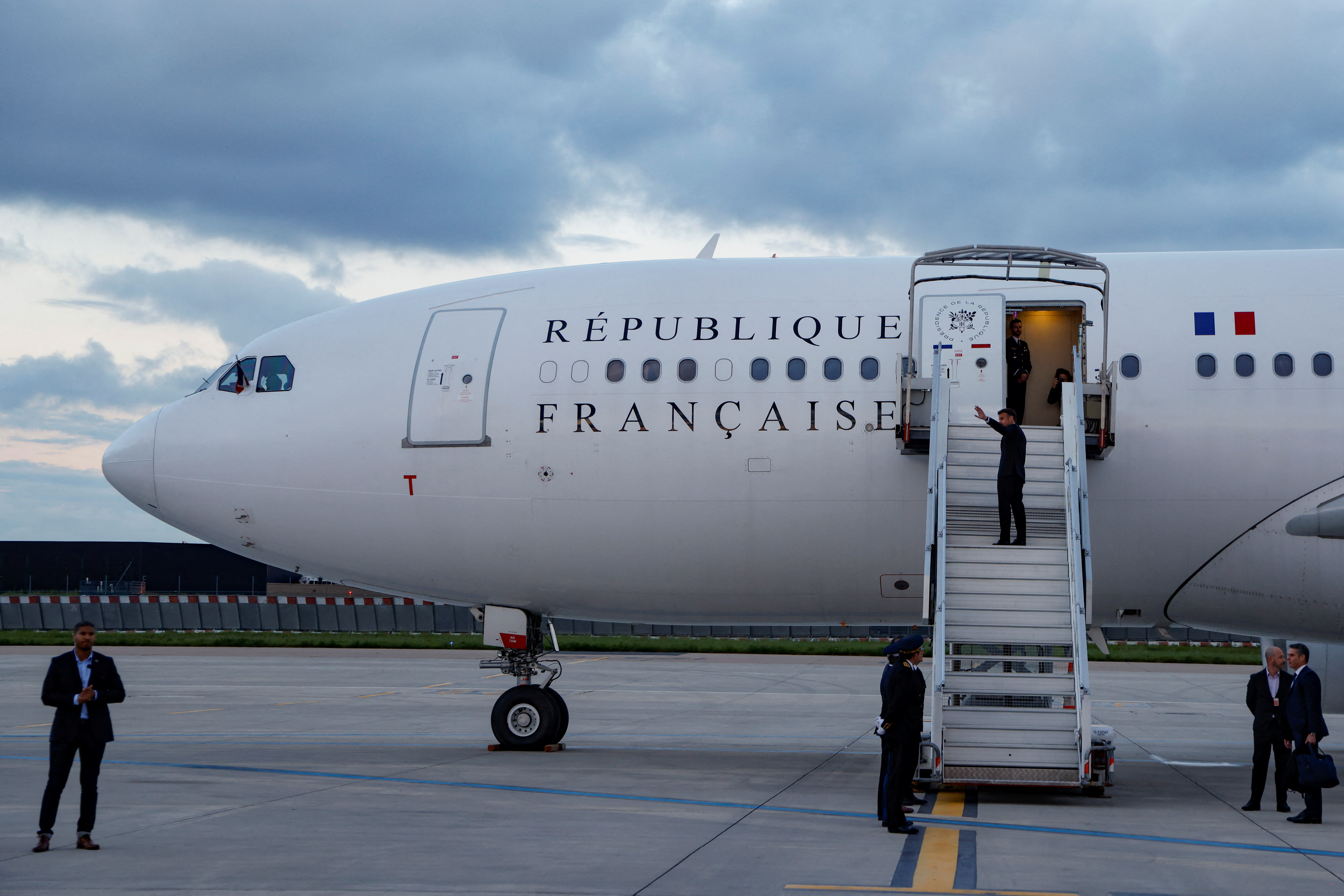France's President Emmanuel Macron waves as he boards his Presidential plane to travel to the Pacific archipelago of New Caledonia