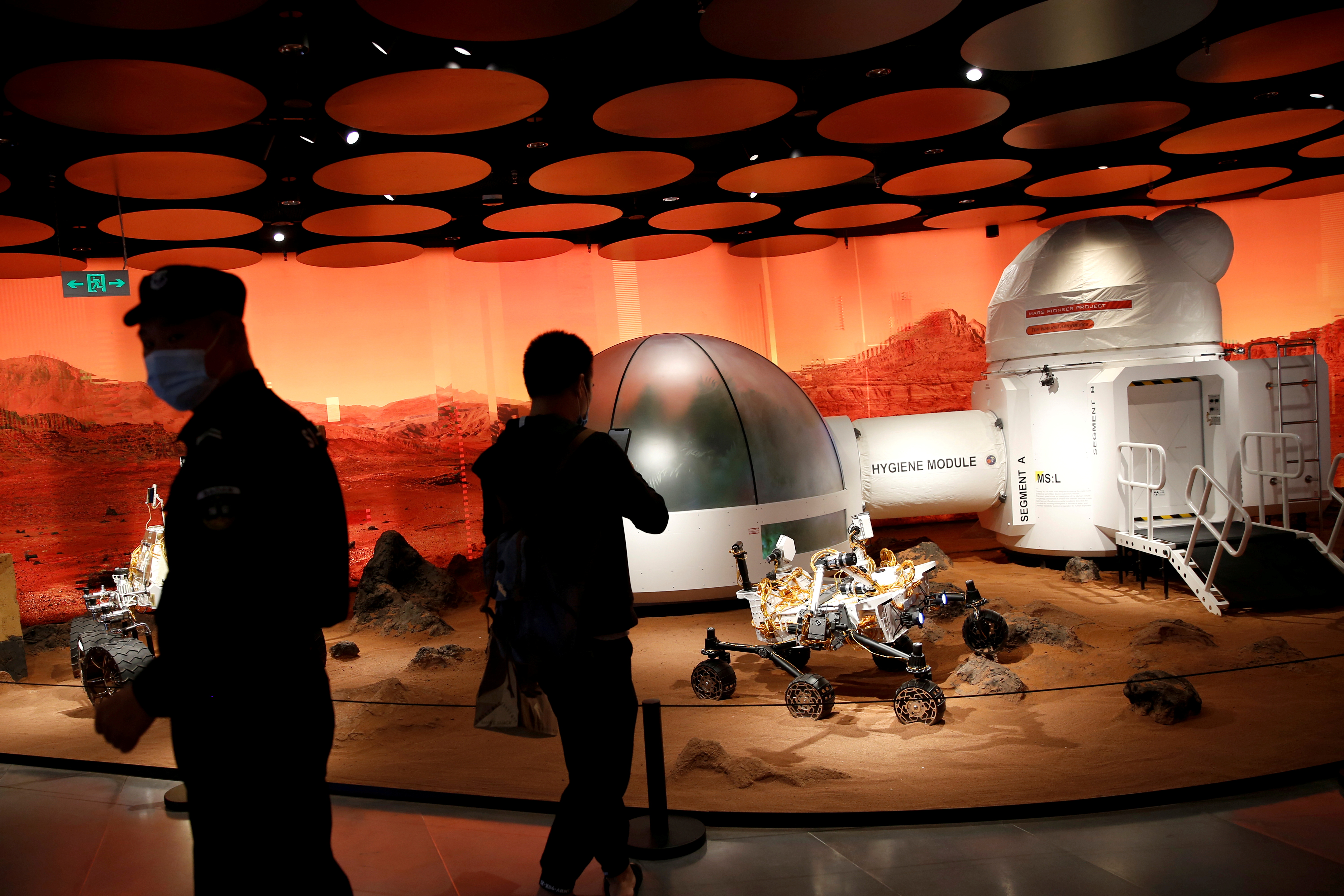 People wearing face masks following the COVID-19 outbreak are seen near models of a Mars base and a rover displayed inside the SKP-S shopping mall in Beijing