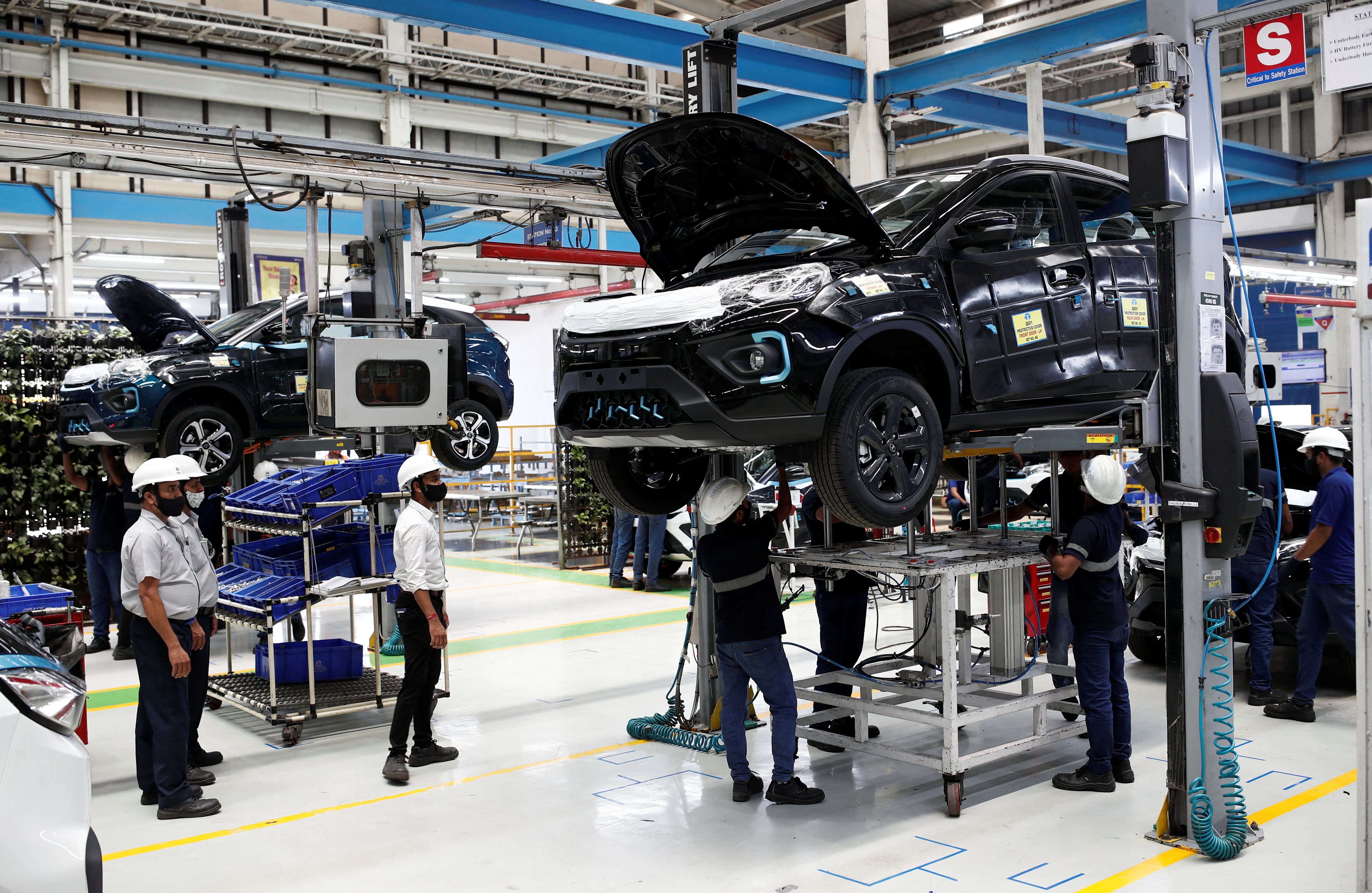 Workers inspect Tata Nexon electric sport utility vehicles (SUV) at a Tata Motors plant in Pune