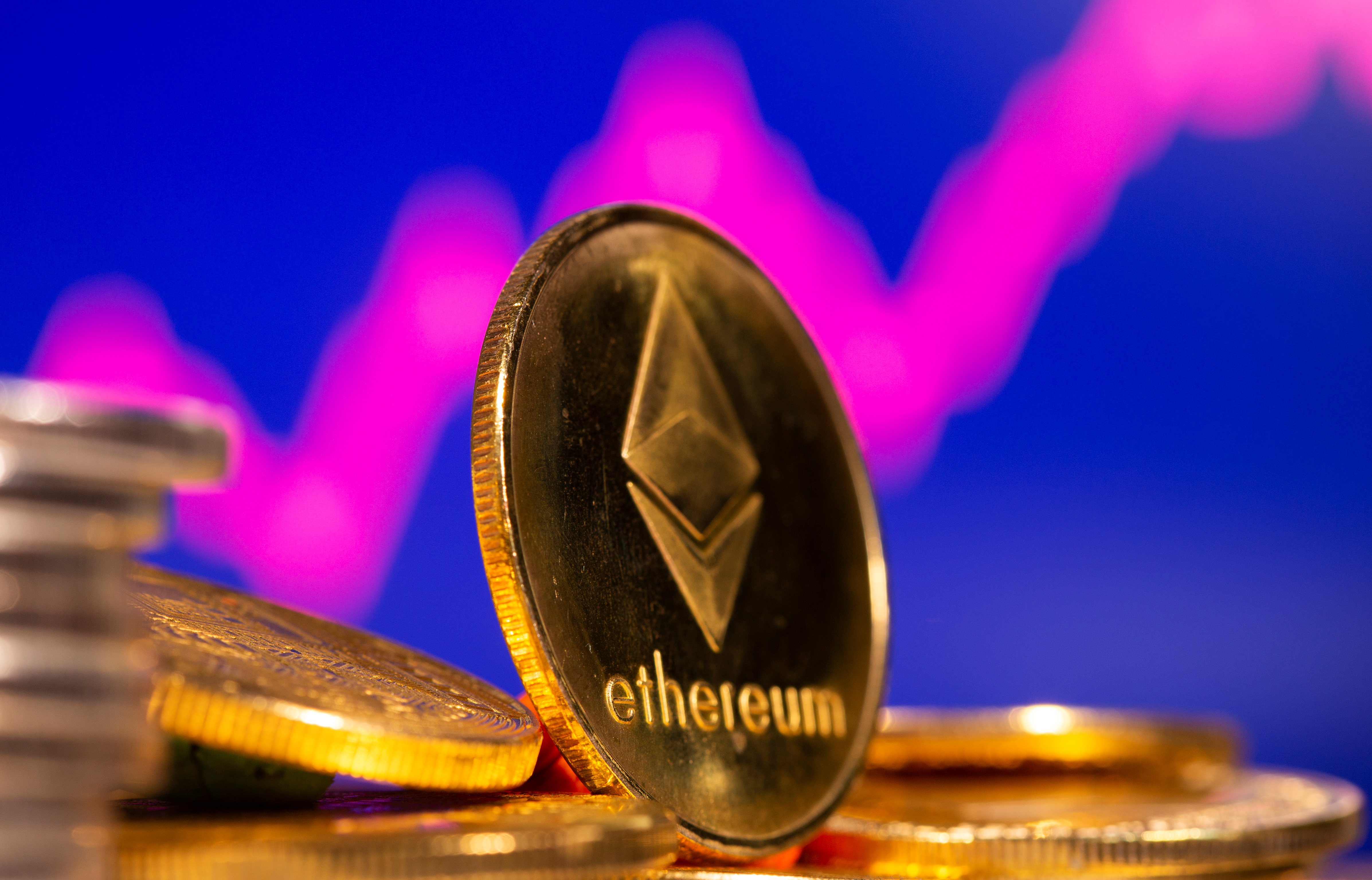 A representation of virtual currency Ethereum are seen in front of a stock graph in this illustration