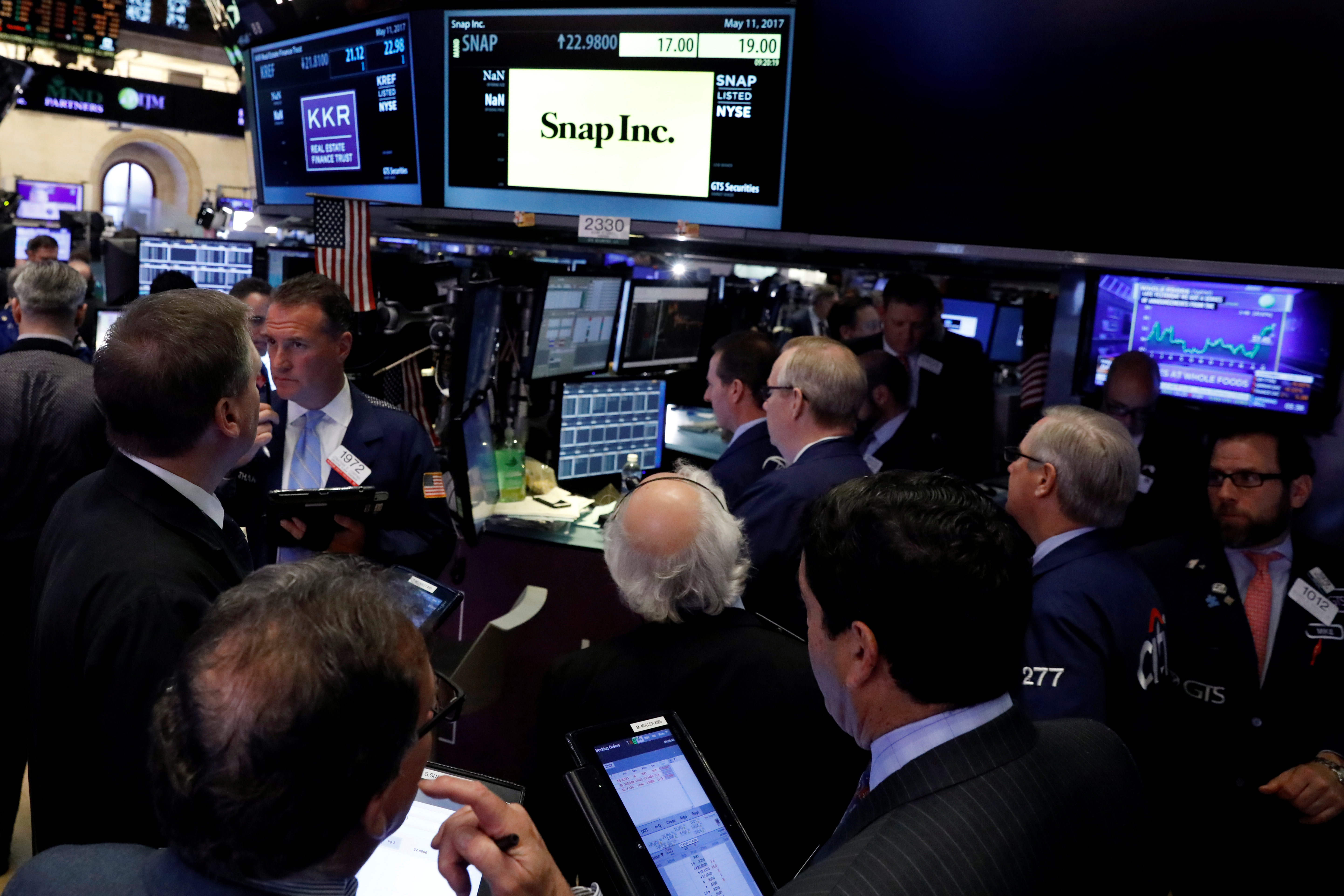 FILE PHOTO - Traders gather at the post where Snap Inc.. is traded, just before the opening bell on the floor of the NYSE in New York