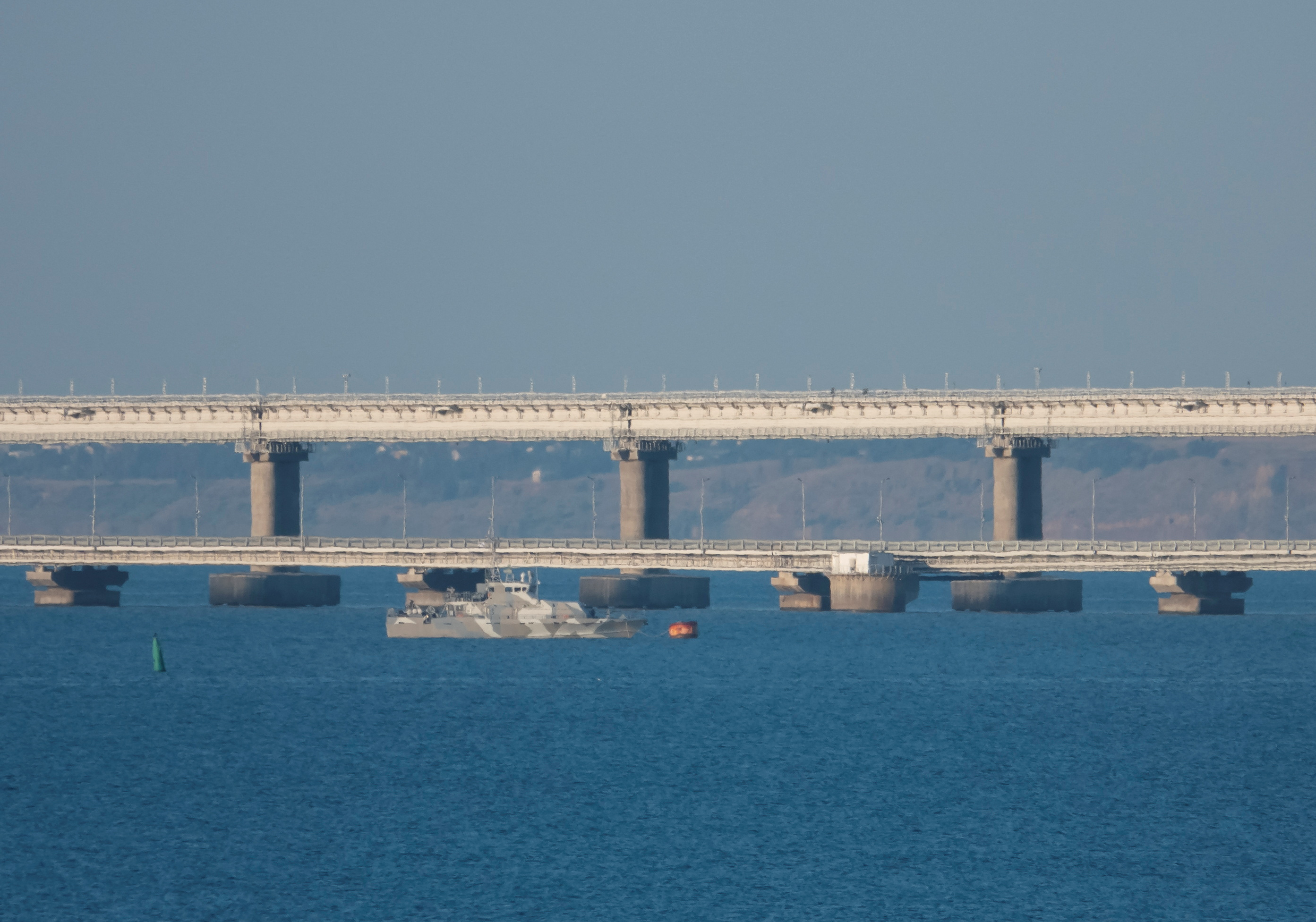 Un barco armado navega junto al puente de Crimea que conecta la parte continental de Rusia con la península a través del estrecho de Kerch.