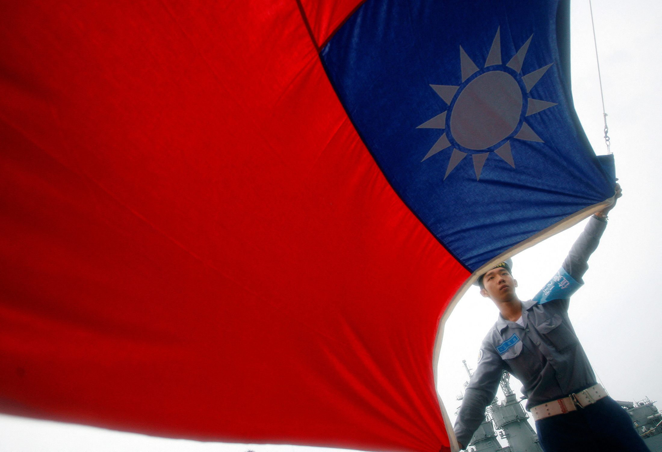 A sailor holds a Taiwan flag on the Navy's 124th fleet Lafayette frigate during a model units tour in Kaohsiung