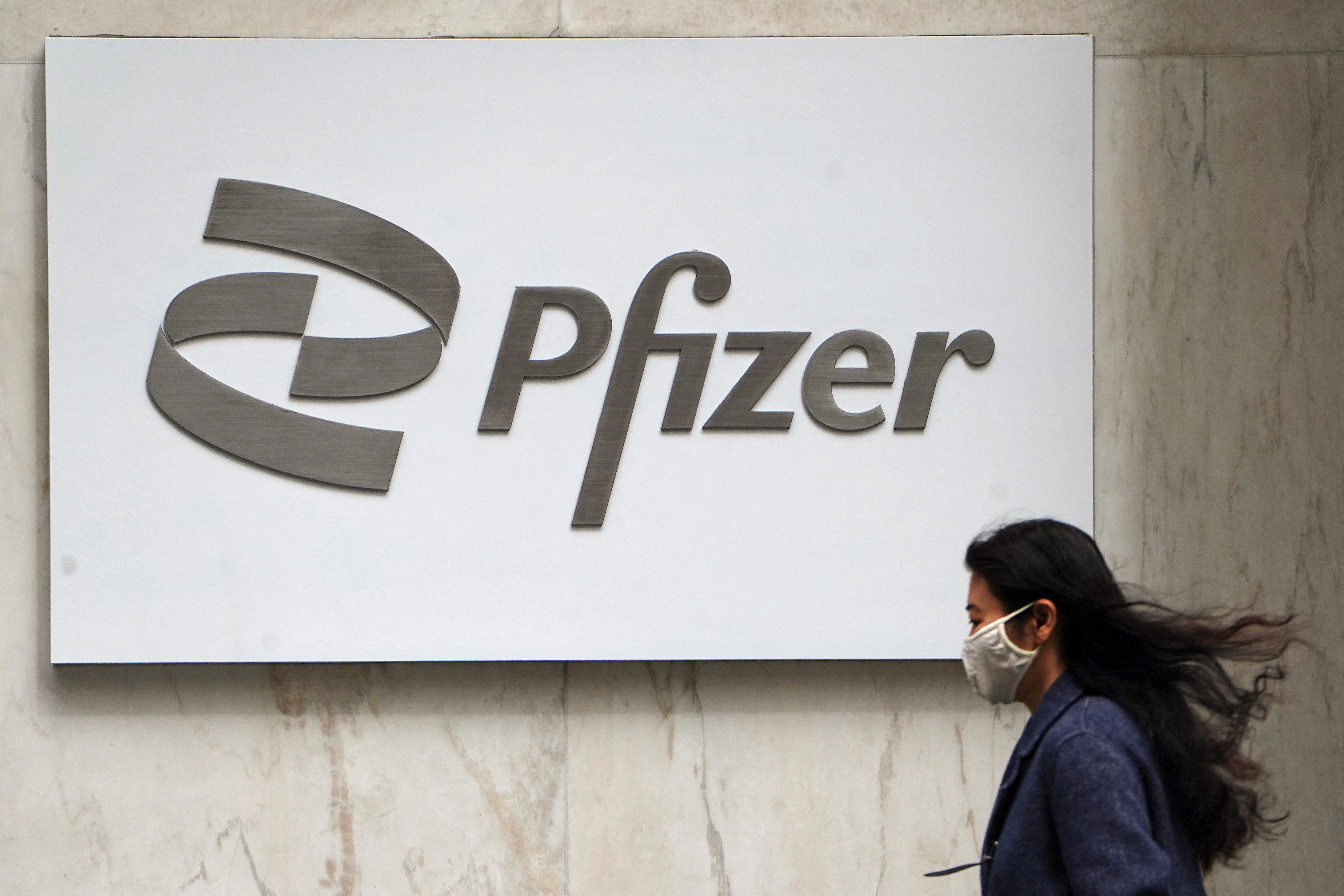 A person walks past a Pfizer logo in New York City