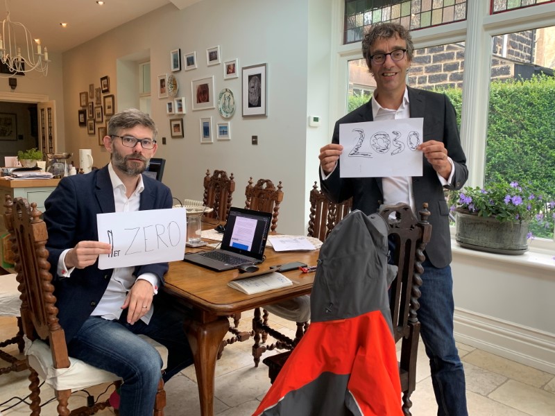Scientists Joeri Rogelj and Piers Forster hold up signs urging reduction in carbon emissions after completing a major U.N. climate report, in a house in Harrogate, Britain August 7, 2021. Picture taken August 7, 2021. Stella Forster/Handout via REUTERS 