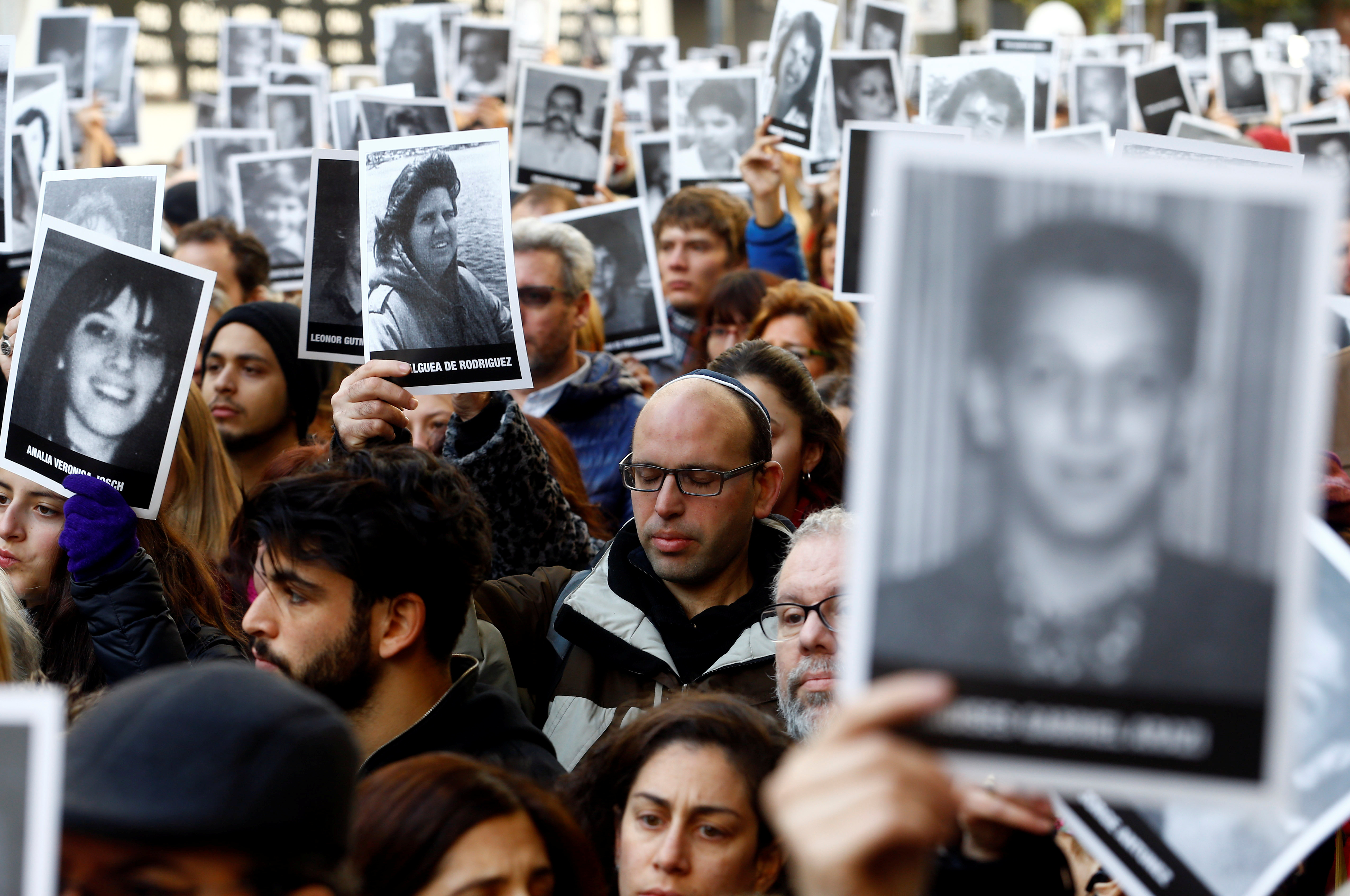 People hold up pictures of the victims of the AMIA Jewish center bombing during a ceremony to mark the 22nd anniversary of the 1994 attack that left 85 dead in Buenos Aires