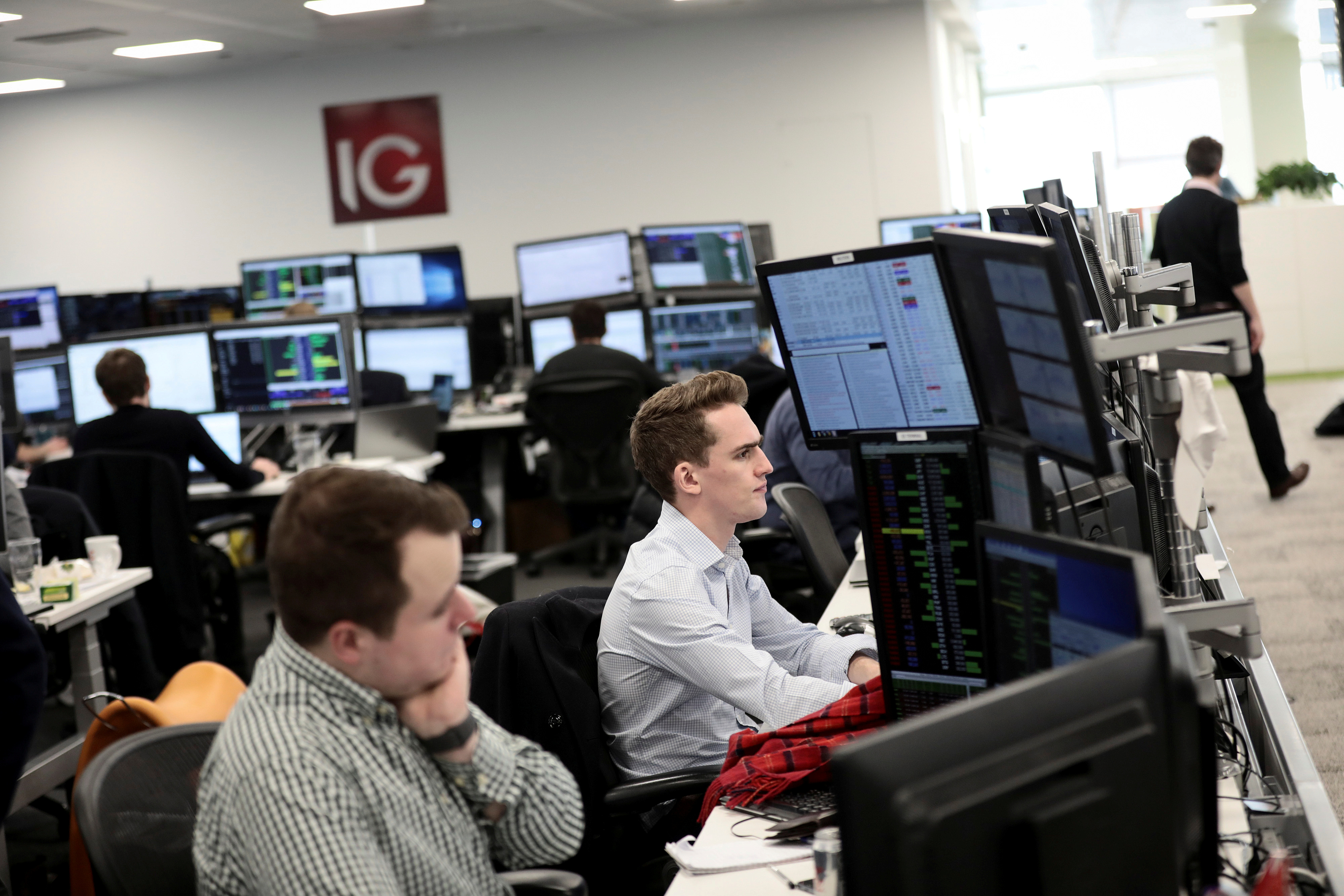Traders look at financial information on computer screens on the IG Index trading floor