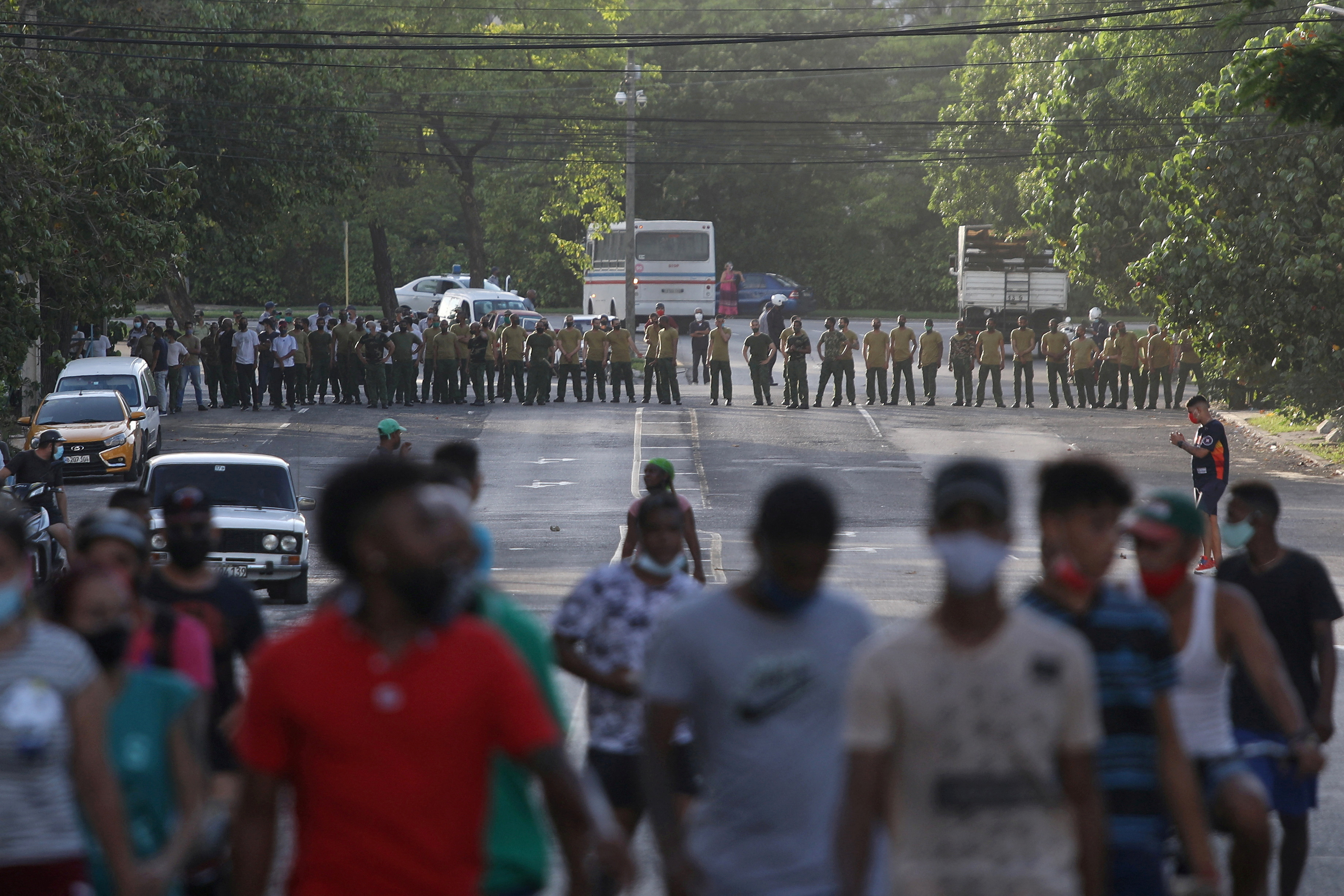 Demonstrators walk away from army soldiers blocking a road during a protest against and in support of the government in Havana