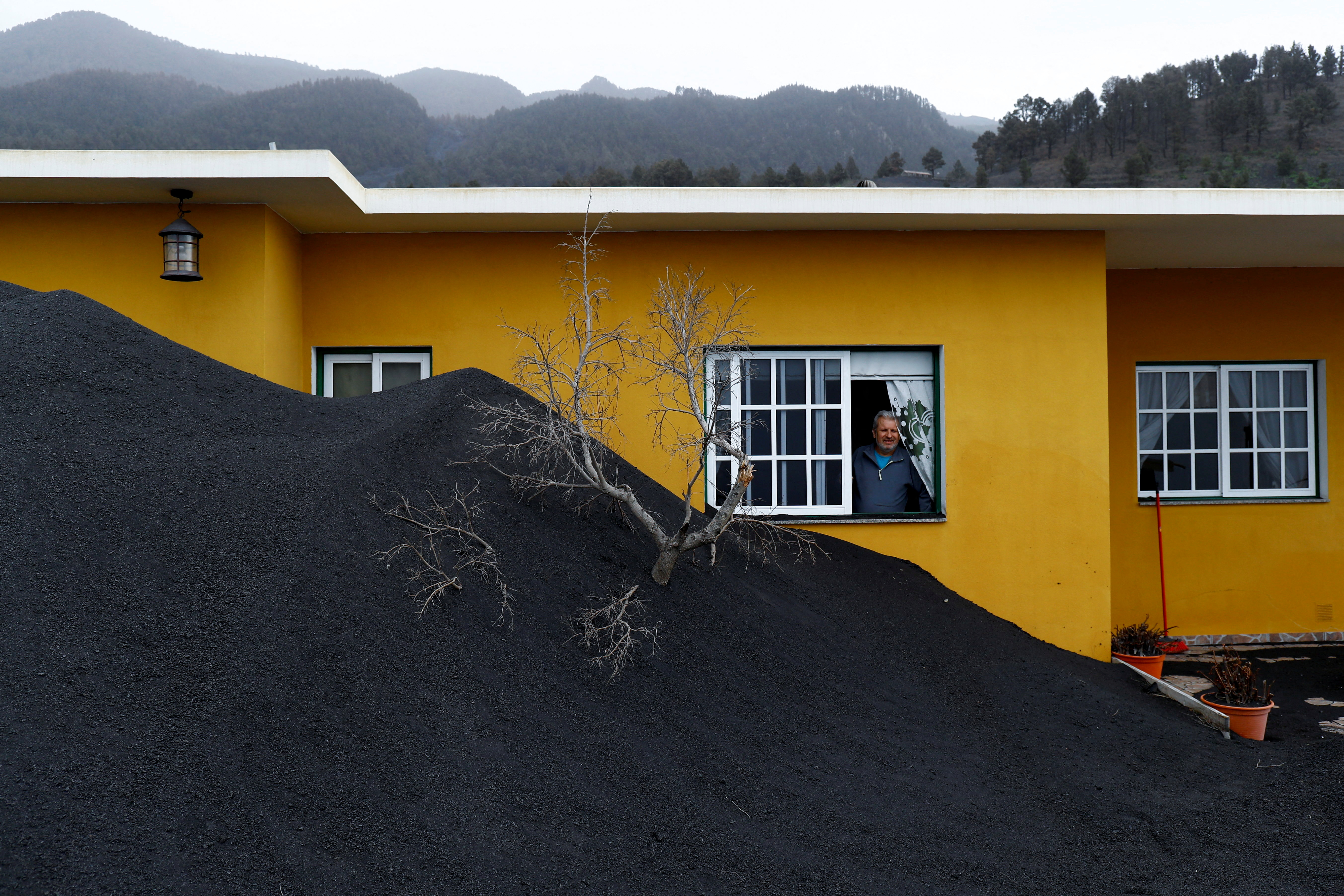 Dionisio Leal looks at heaps of ash from the Cumbre Vieja volcano surrounding his house in Las Manchas neighbourhood