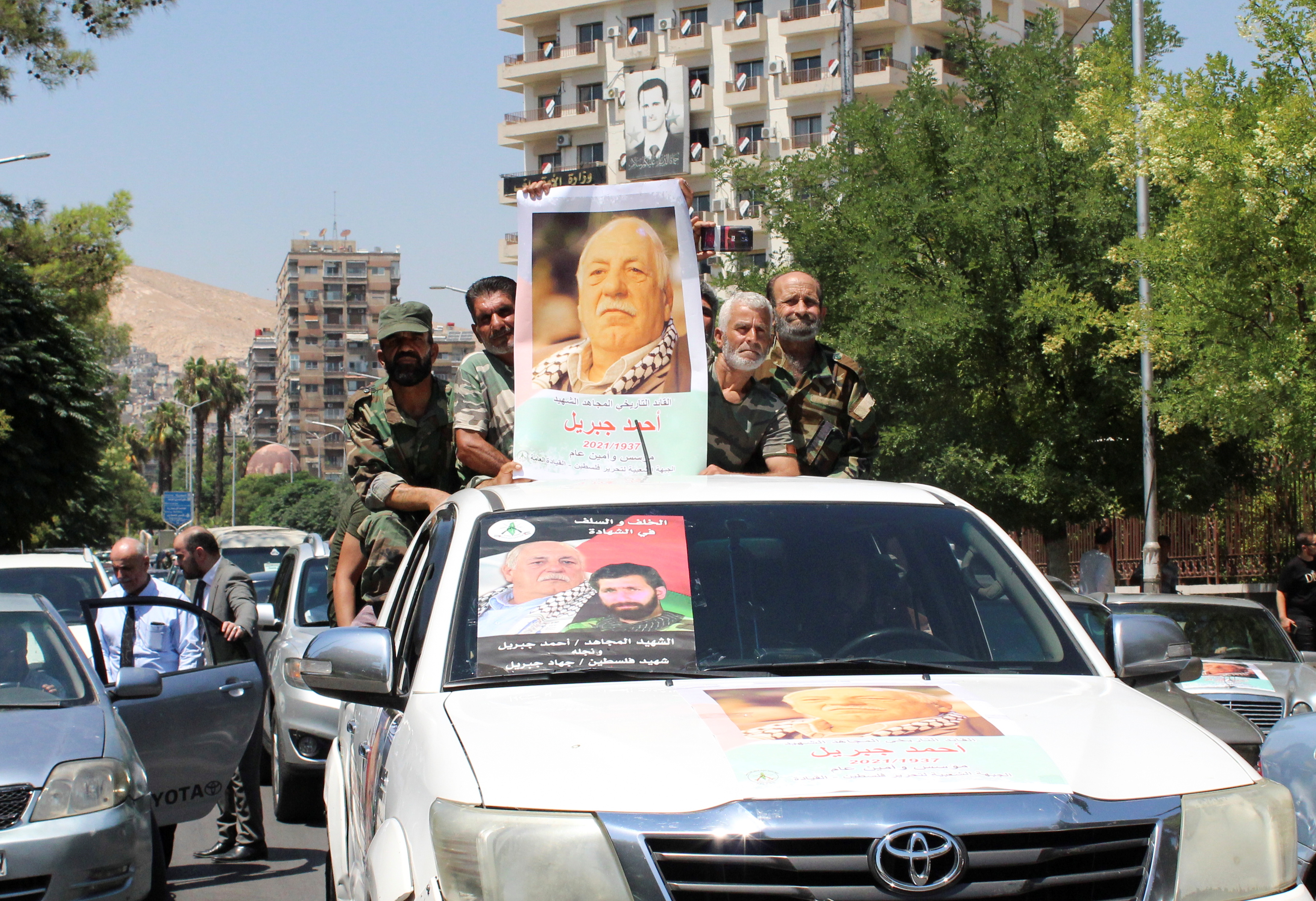 Mourners stand on a back of a vehicle as they hold a picture of Ahmed Jibril, founder of pro-Syrian Palestinian guerrilla faction during his funeral in Damascus