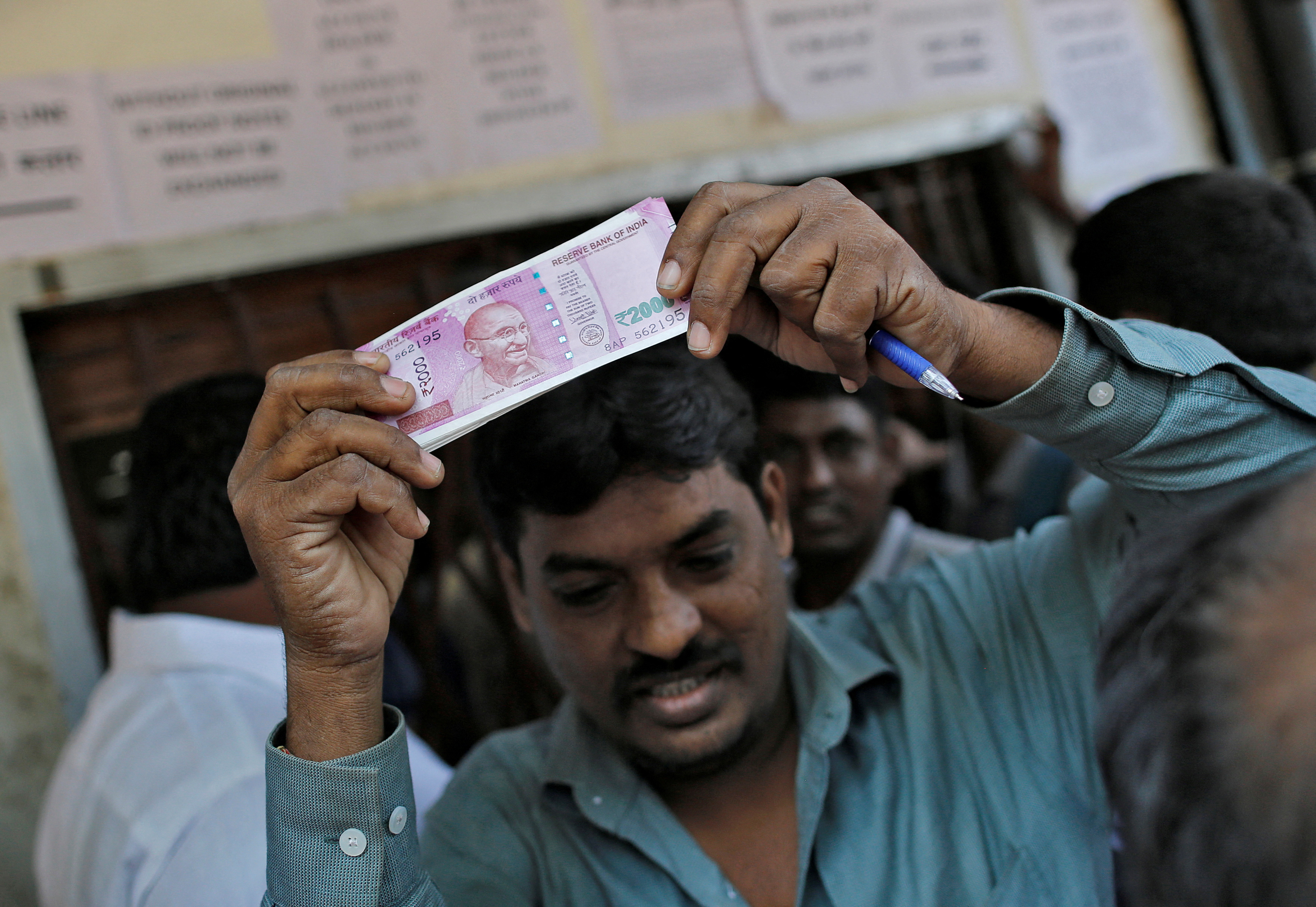 People queue as they wait for their turn to exchange or deposit their old high denomination banknotes outside a bank in Mumbai