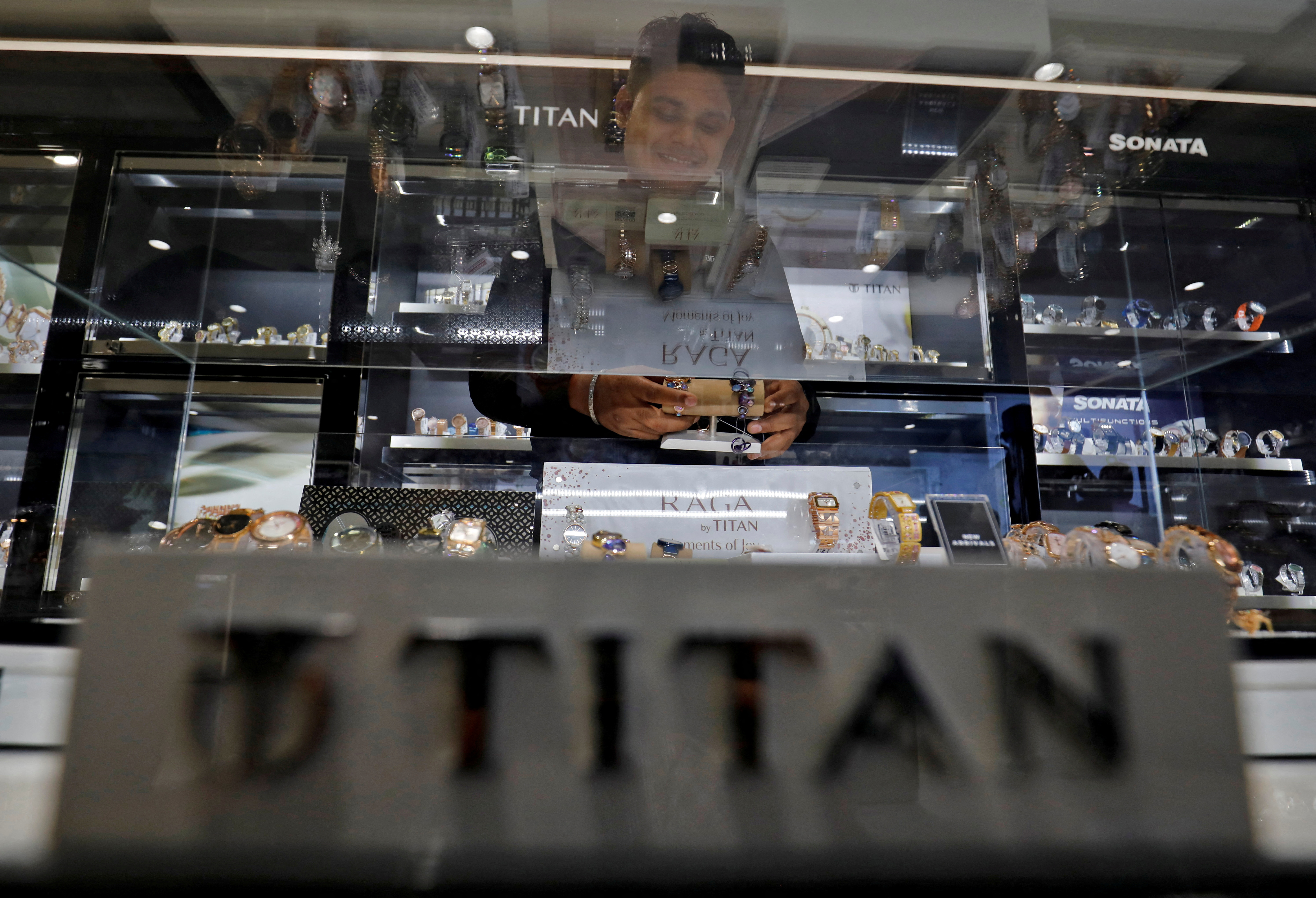 A salesperson arranges wristwatches inside Titan World showroom in Ahmedabad