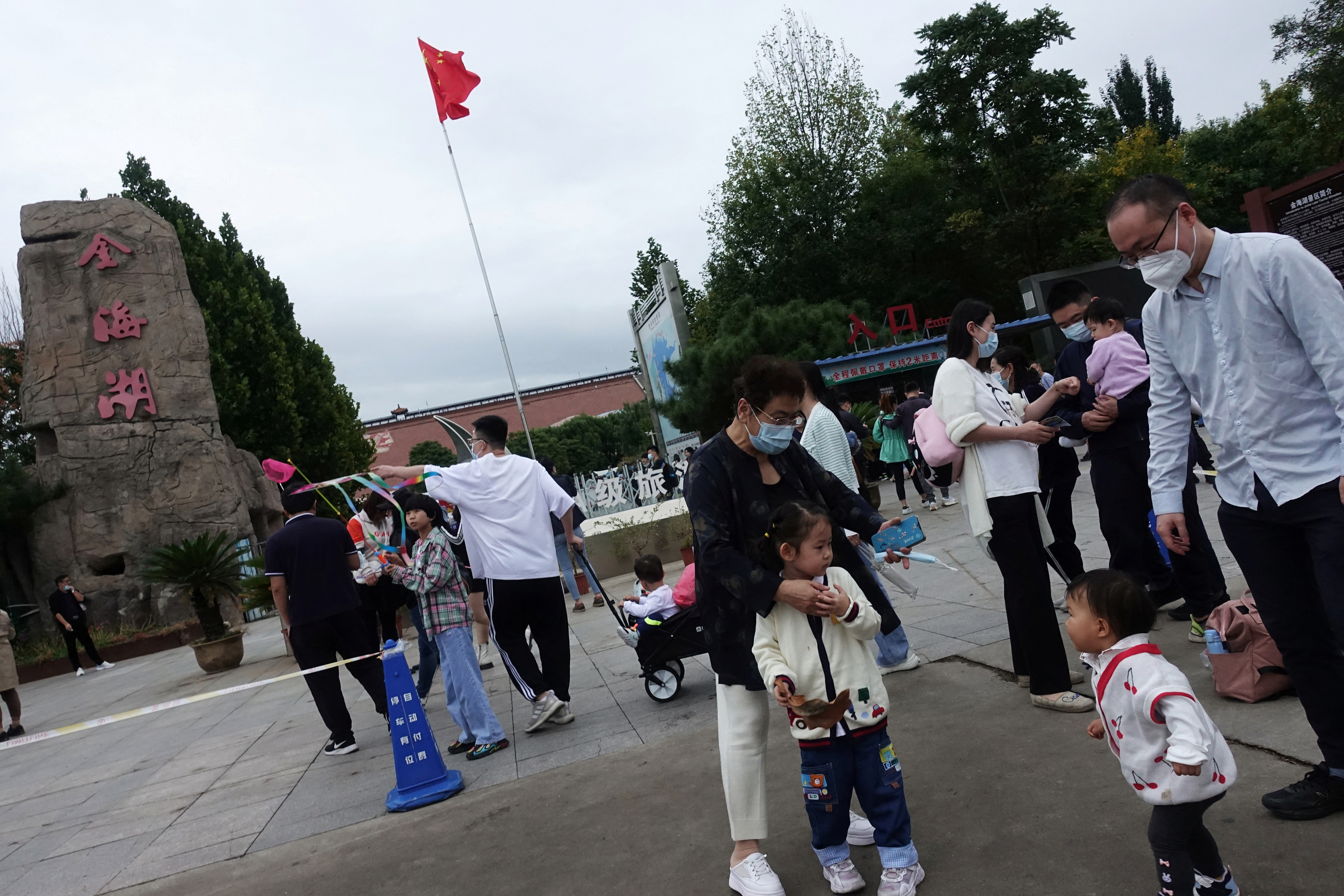 Tourists stand near a Chinese national flag at a tourist site during the National Day holiday, in the outskirts of Beijing