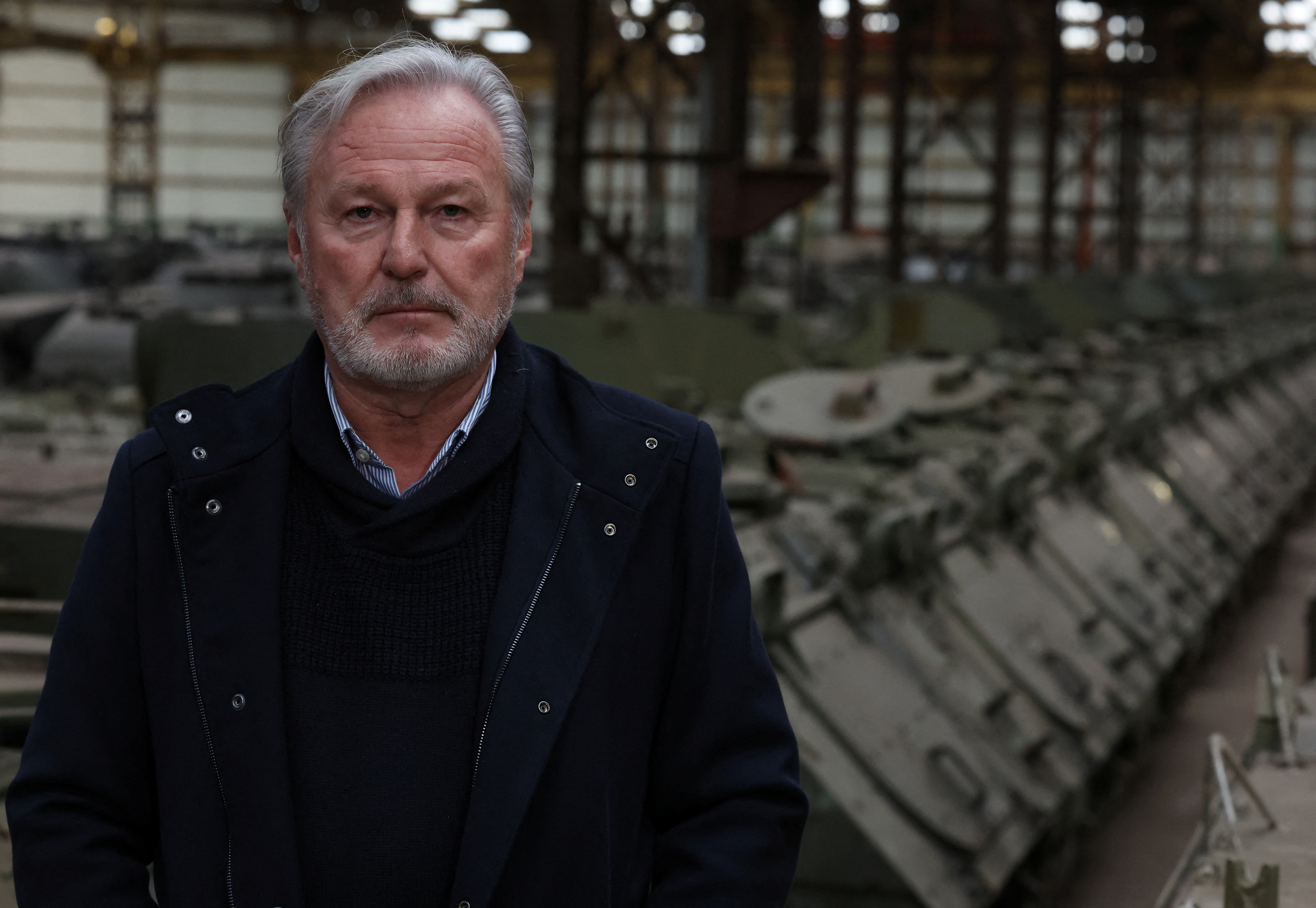 Freddy Versluys, CEO of Belgian defense company OIP Land Systems, looks at nearby armored vehicles in a hangar in Tournais