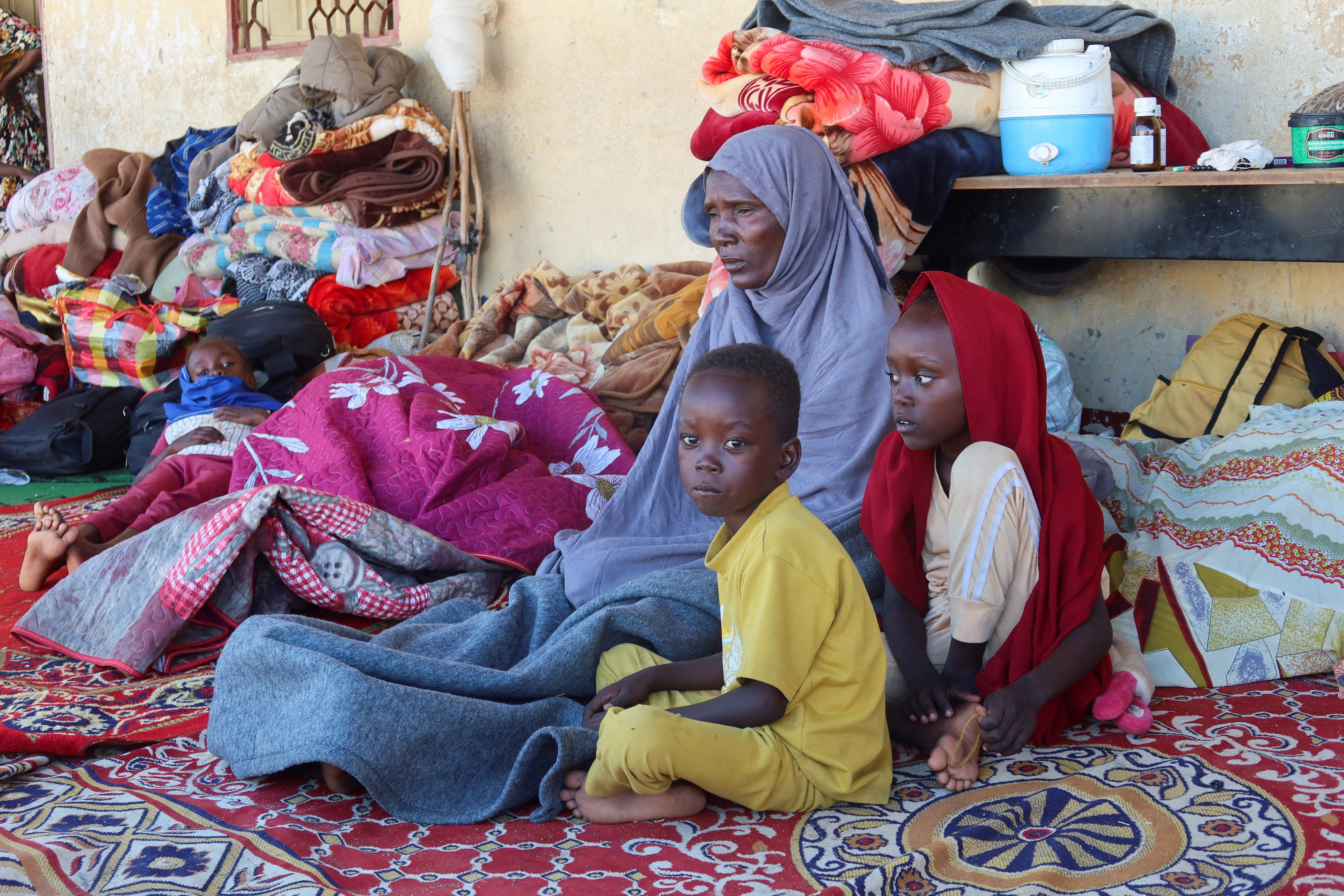 A Sudanese family, displaced from Gezira state due to RSF violence, sit at a shelter in New Halfa