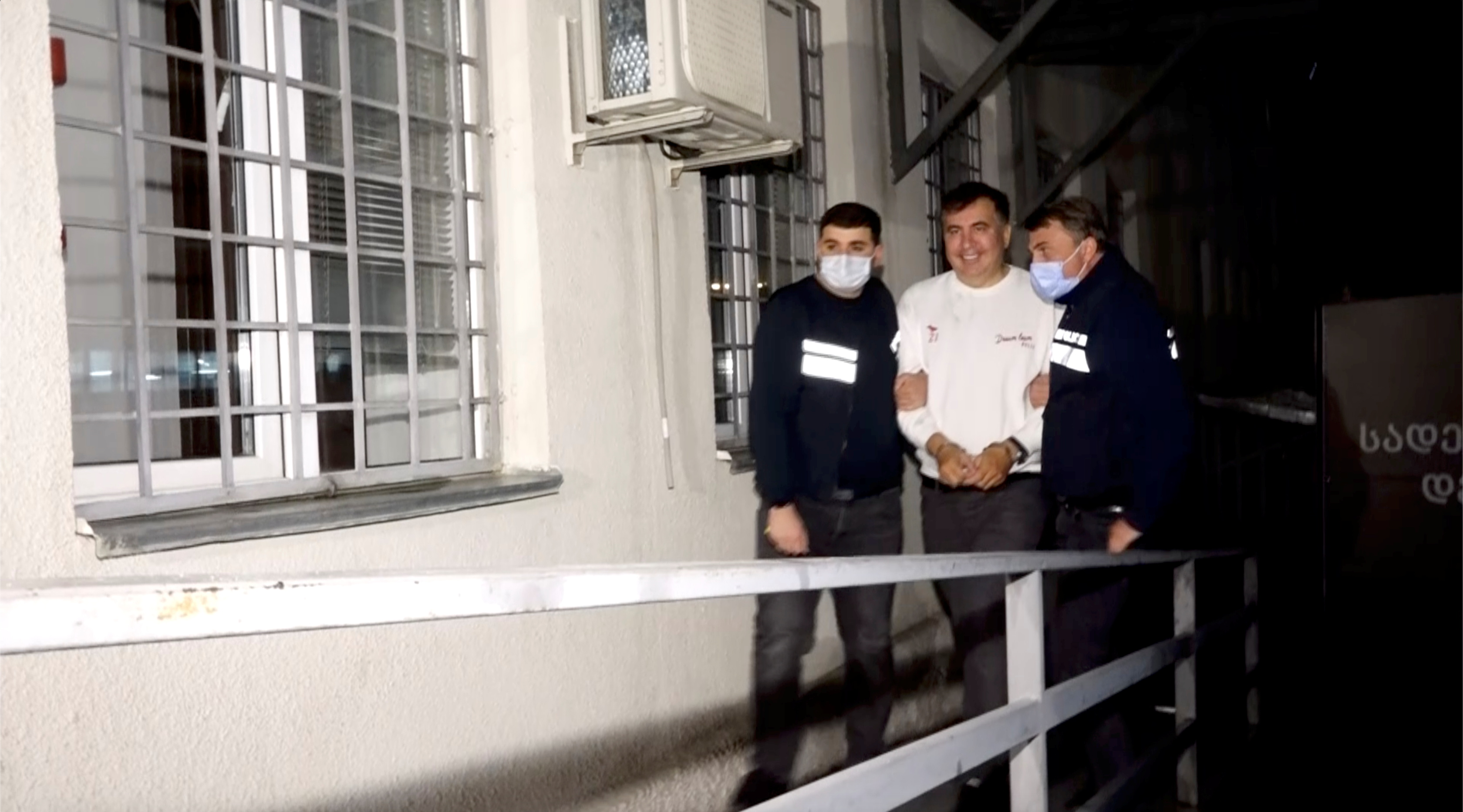 Georgia's former President Mikheil Saakashvili is escorted by police officers as he arrives at a prison in Rustavi