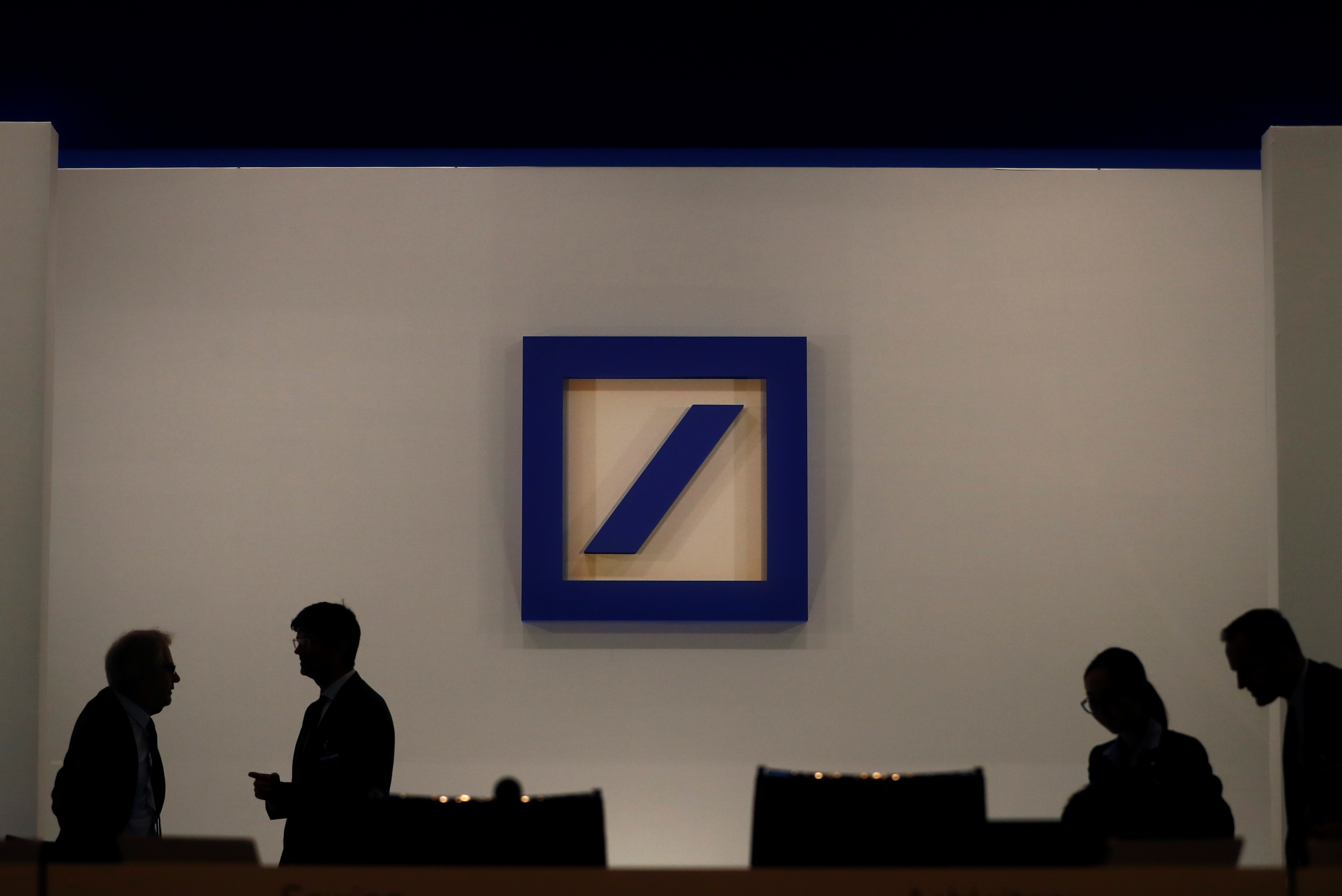 People are silhouetted next to the Deutsche Bank's logo prior to the bank's annual meeting in Frankfurt, Germany, May 24, 2018. REUTERS/Kai Pfaffenbach
