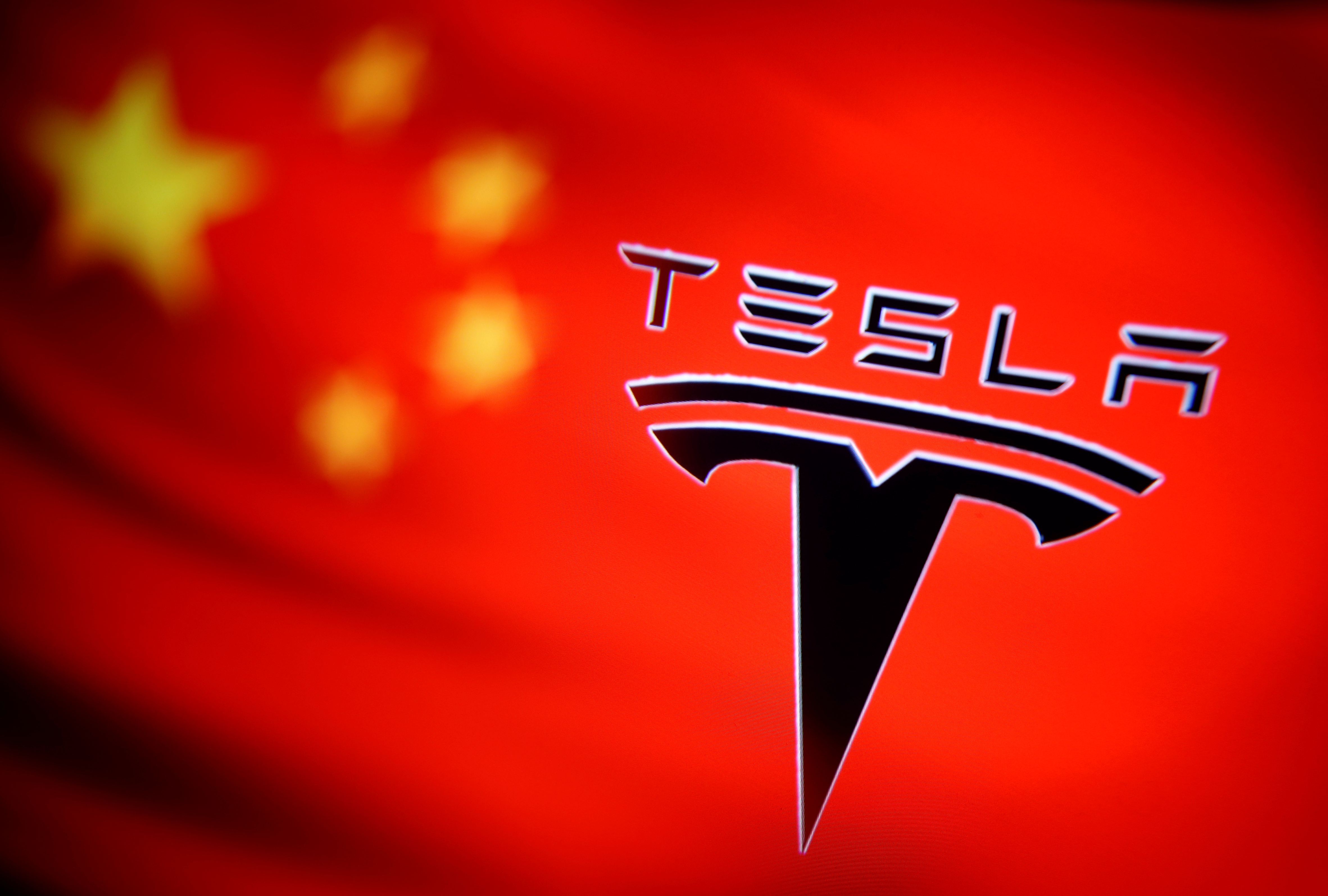 Chinese flag and Tesla logo is seen through a magnifier in this illustration taken January 7, 2021. REUTERS/Dado Ruvic