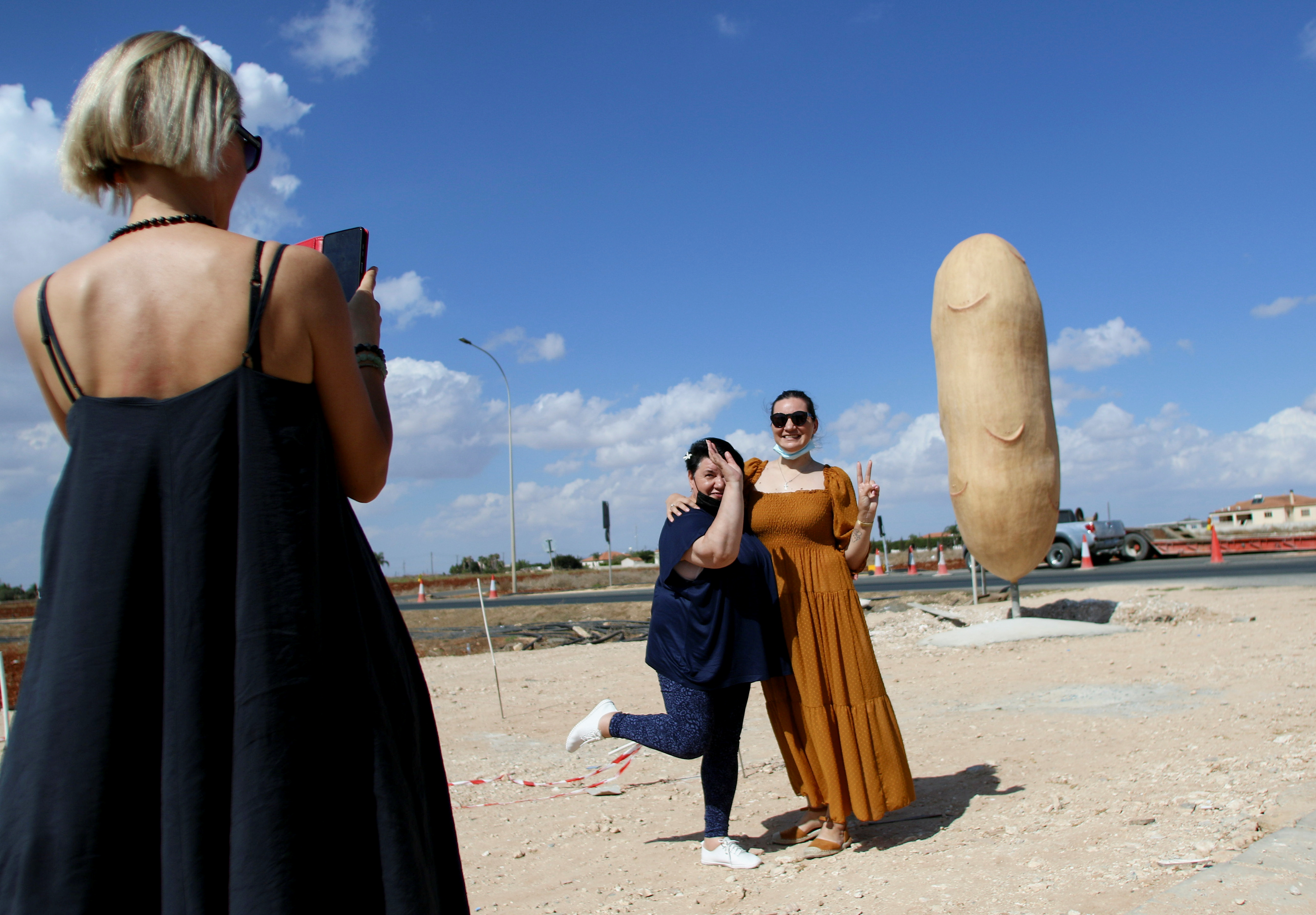 People pose for a picture next to a 5 meter high replica of a potato in Xylophagou village