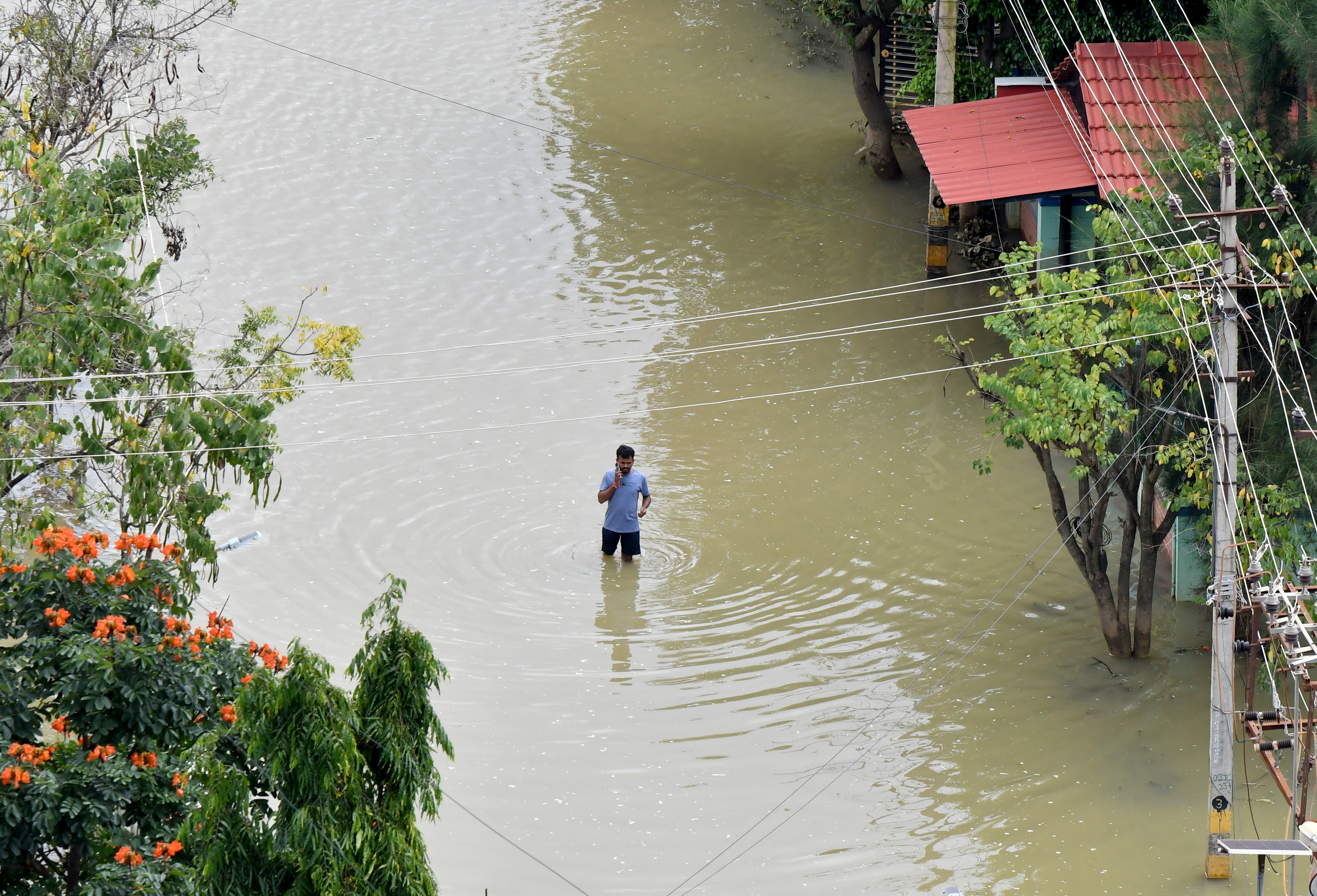 A man speaks on his mobile phone as he wades through a water-logged road in a residential area following torrential rains in Bengaluru