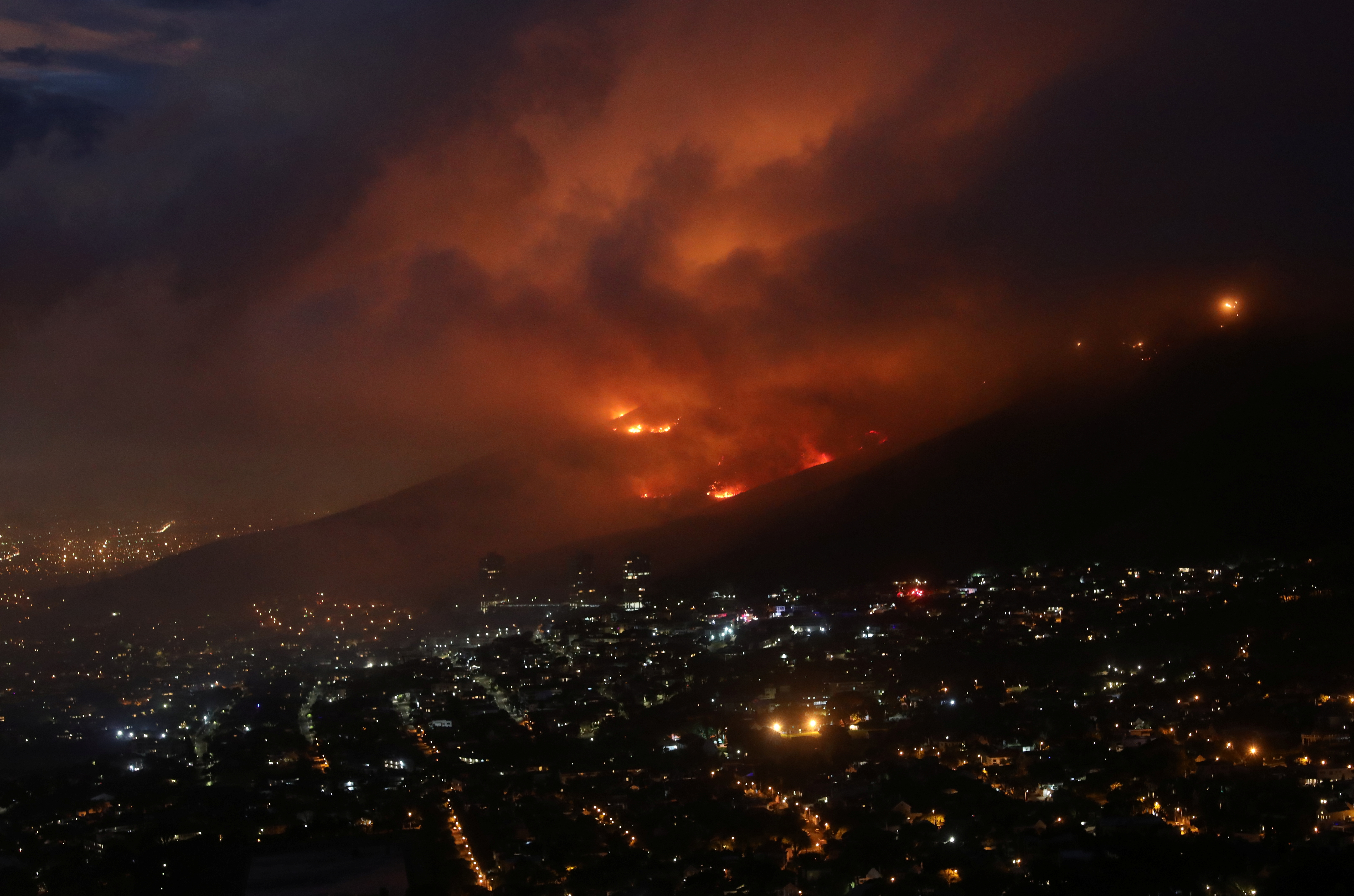 Flames are seen close to the city fanned by strong winds after  a bushfire  broke out on the slopes of Table Mountain in Cape Town, South Africa, April 19, 2021. REUTERS/Mike Hutchings