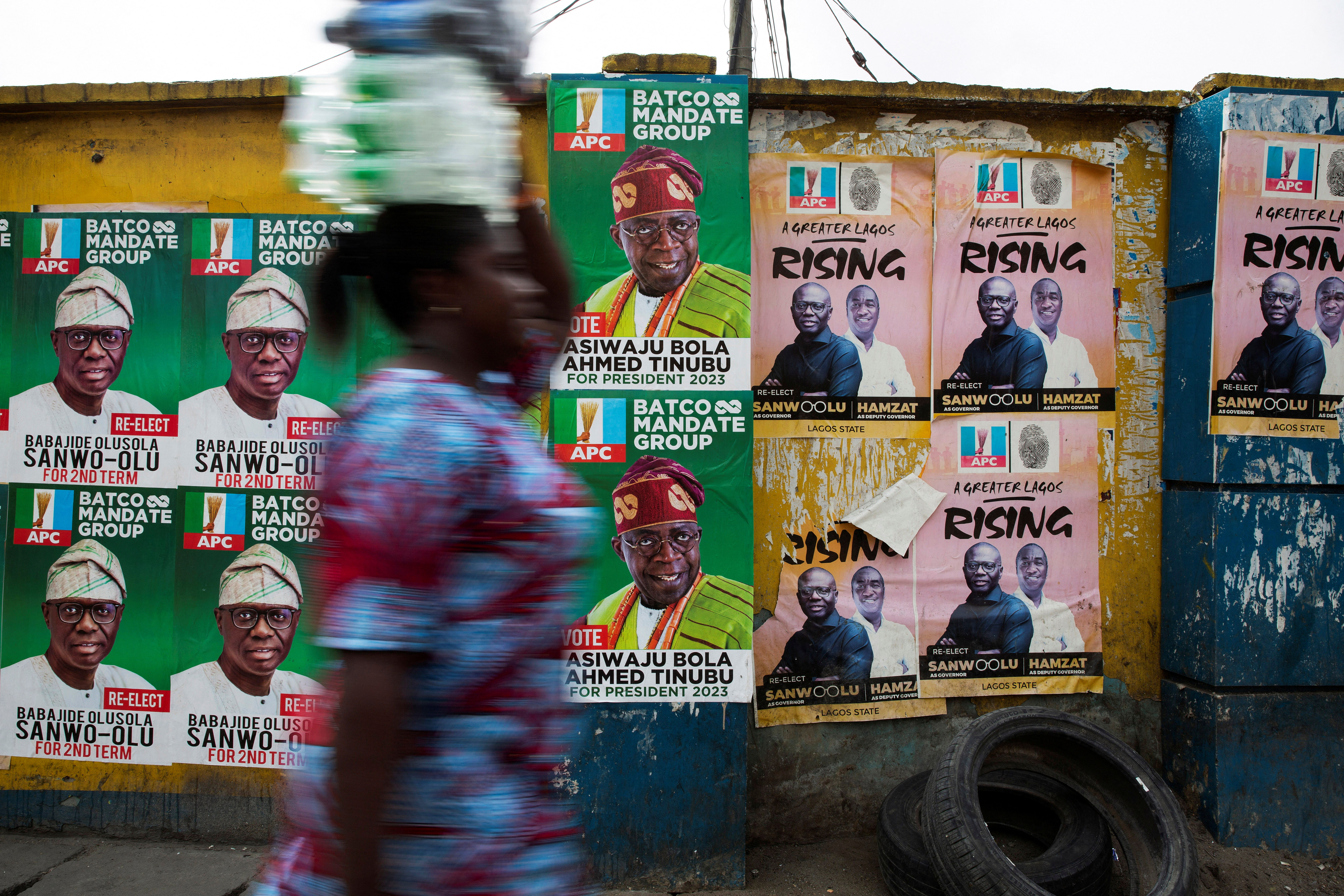 A woman walks past election posters in Lagos