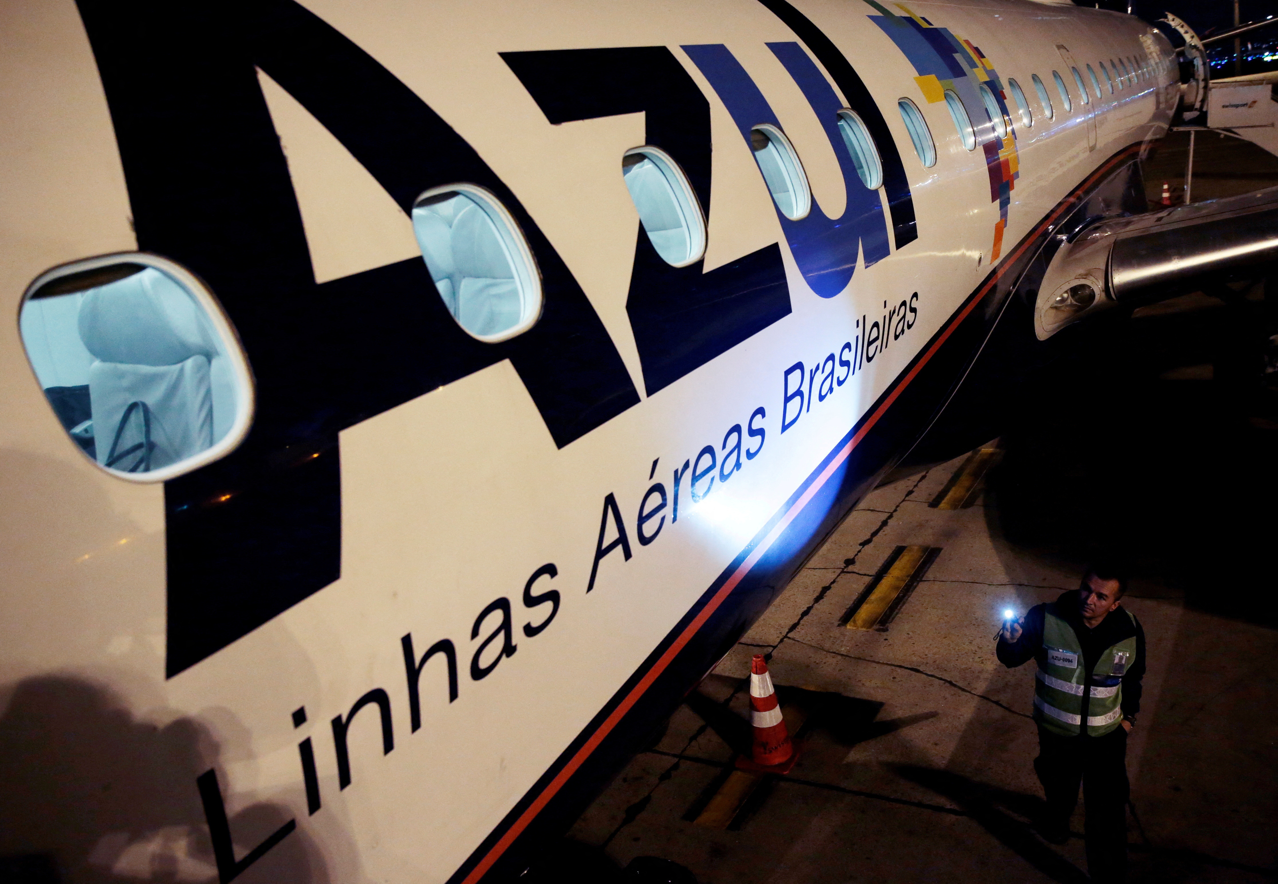 An employee of Azul Brazilian Airlines checks the Embraer 190 plane at International Airport in Guarulhos