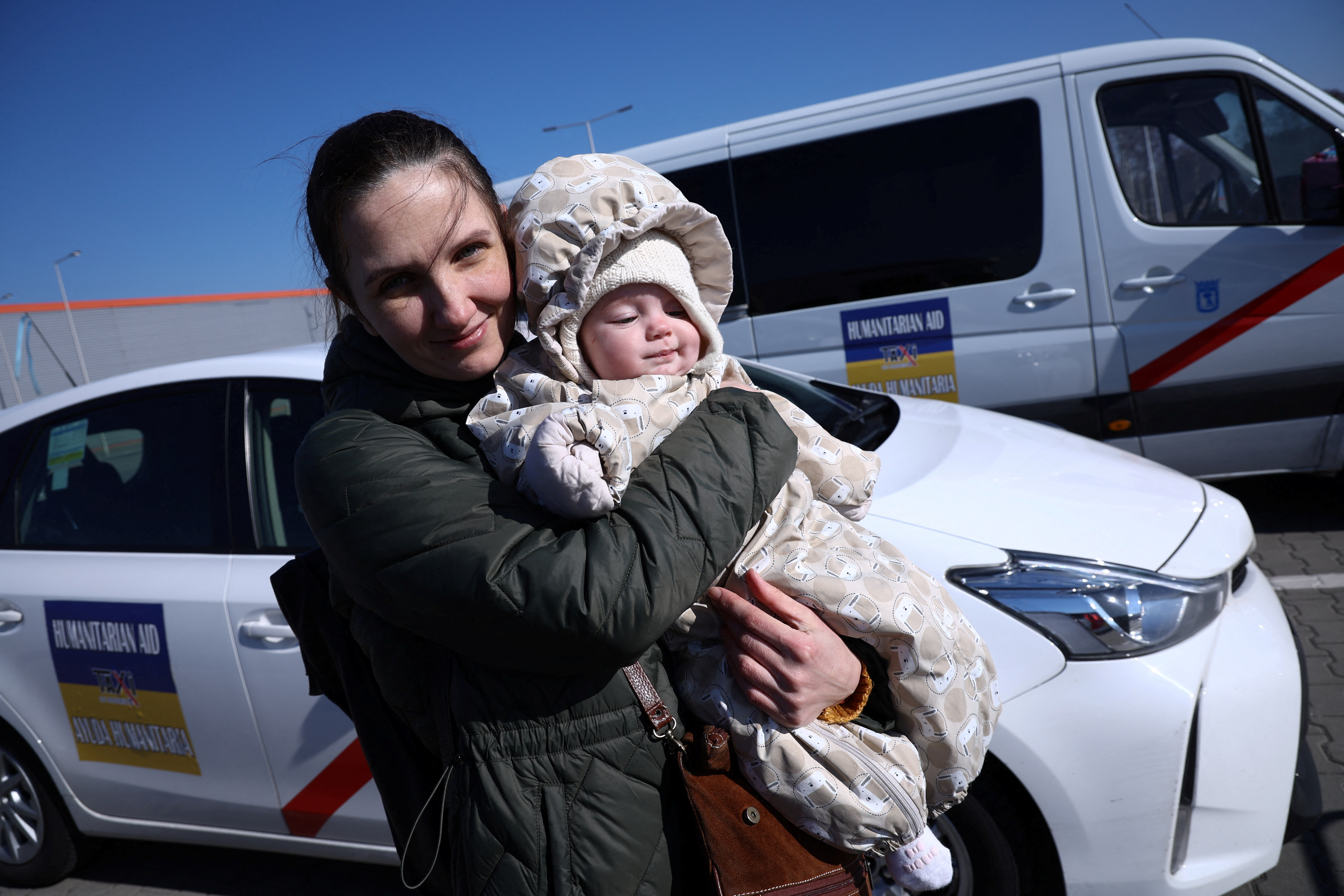 Ukrainian woman Olga, 38, holds her 6-month-old daughter Vera in front of the reception center for refugees, in Nadarzyn