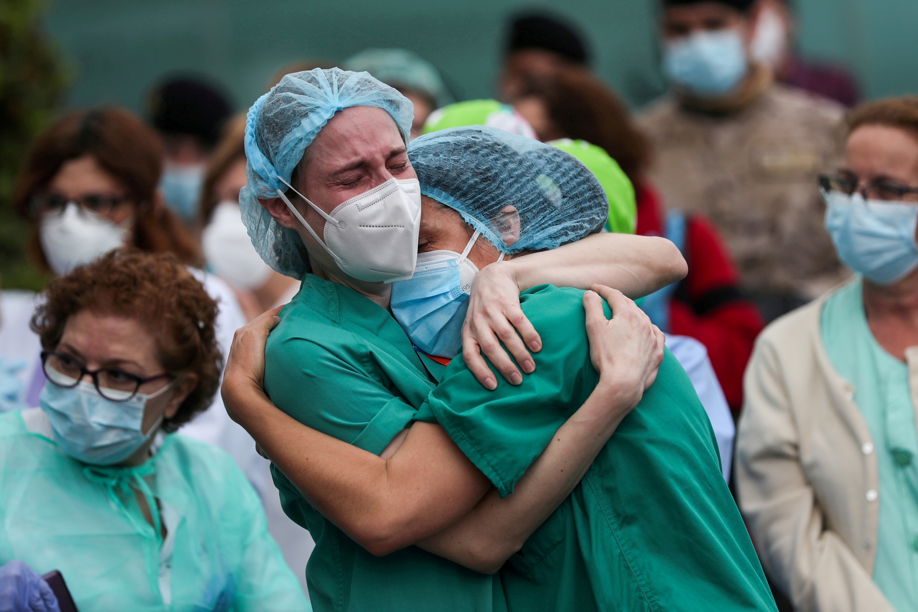 Health workers wearing protective face masks react during a tribute for a co-worker who died in Leganes