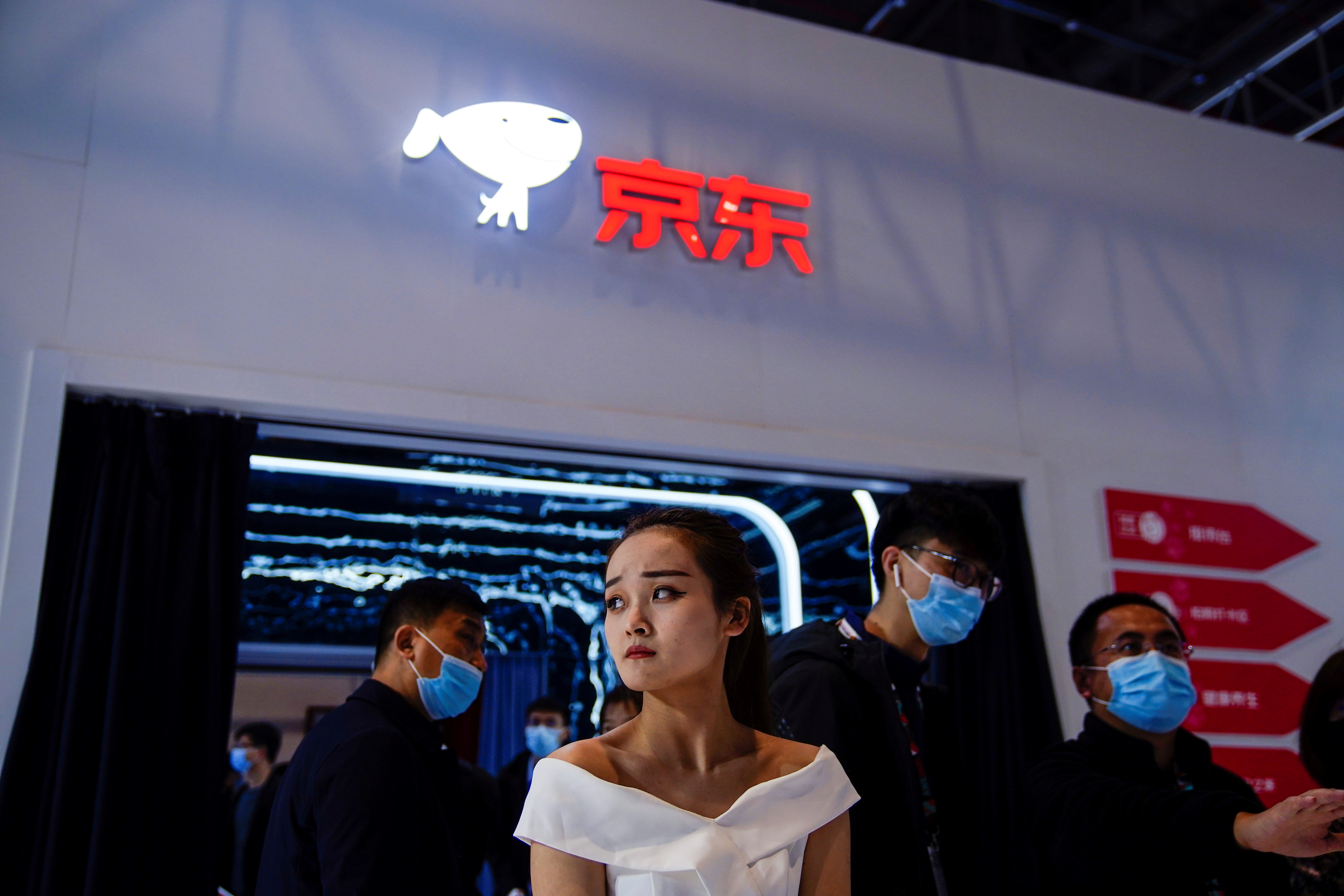 People stand under a JD.com company sign at the Appliance and Electronics World Expo (AWE) in Shanghai