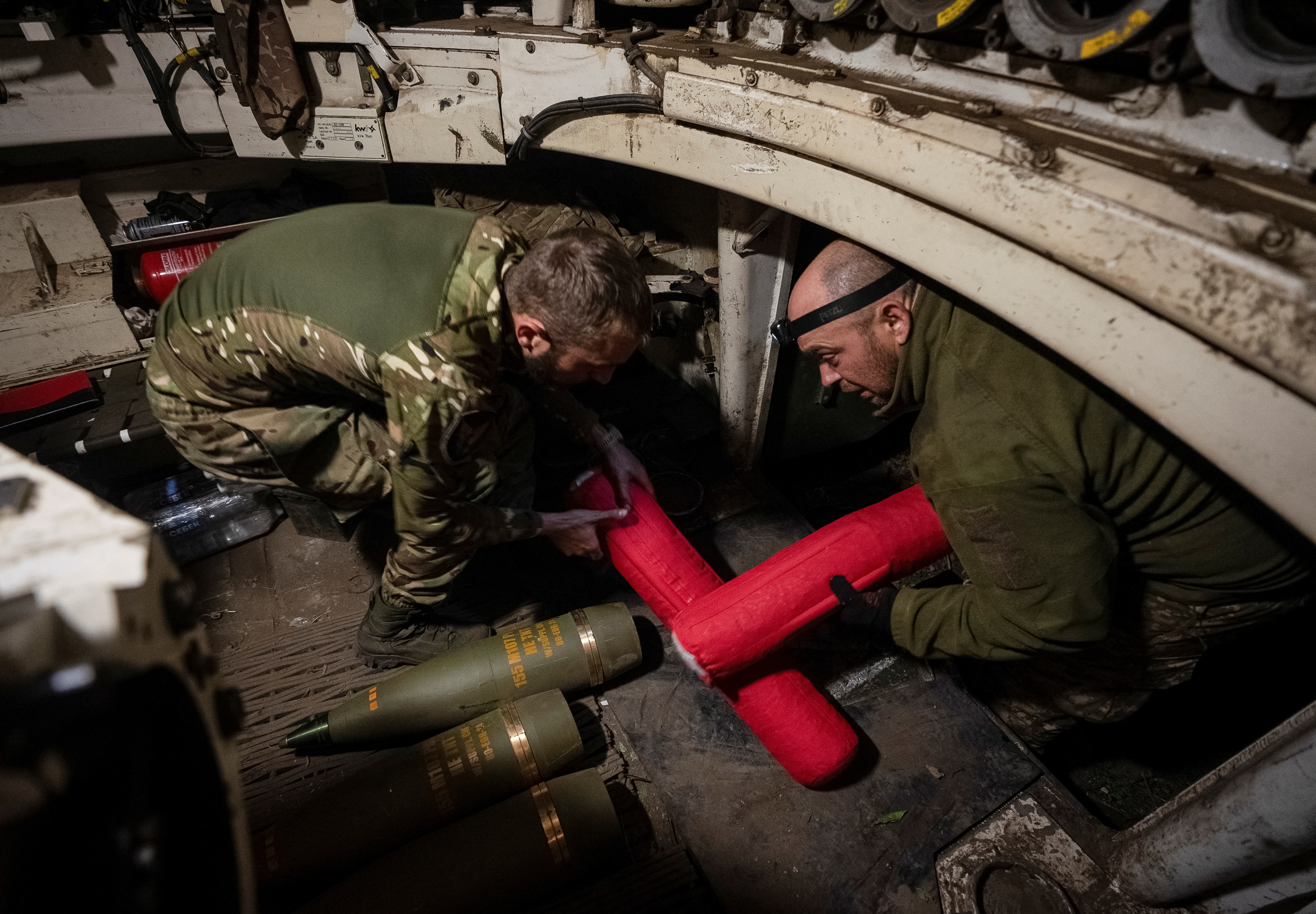 Ukrainian servicemen load shells in an M109 self-propelled howitzer before firing towards Russian troops near the town of Vovchansk