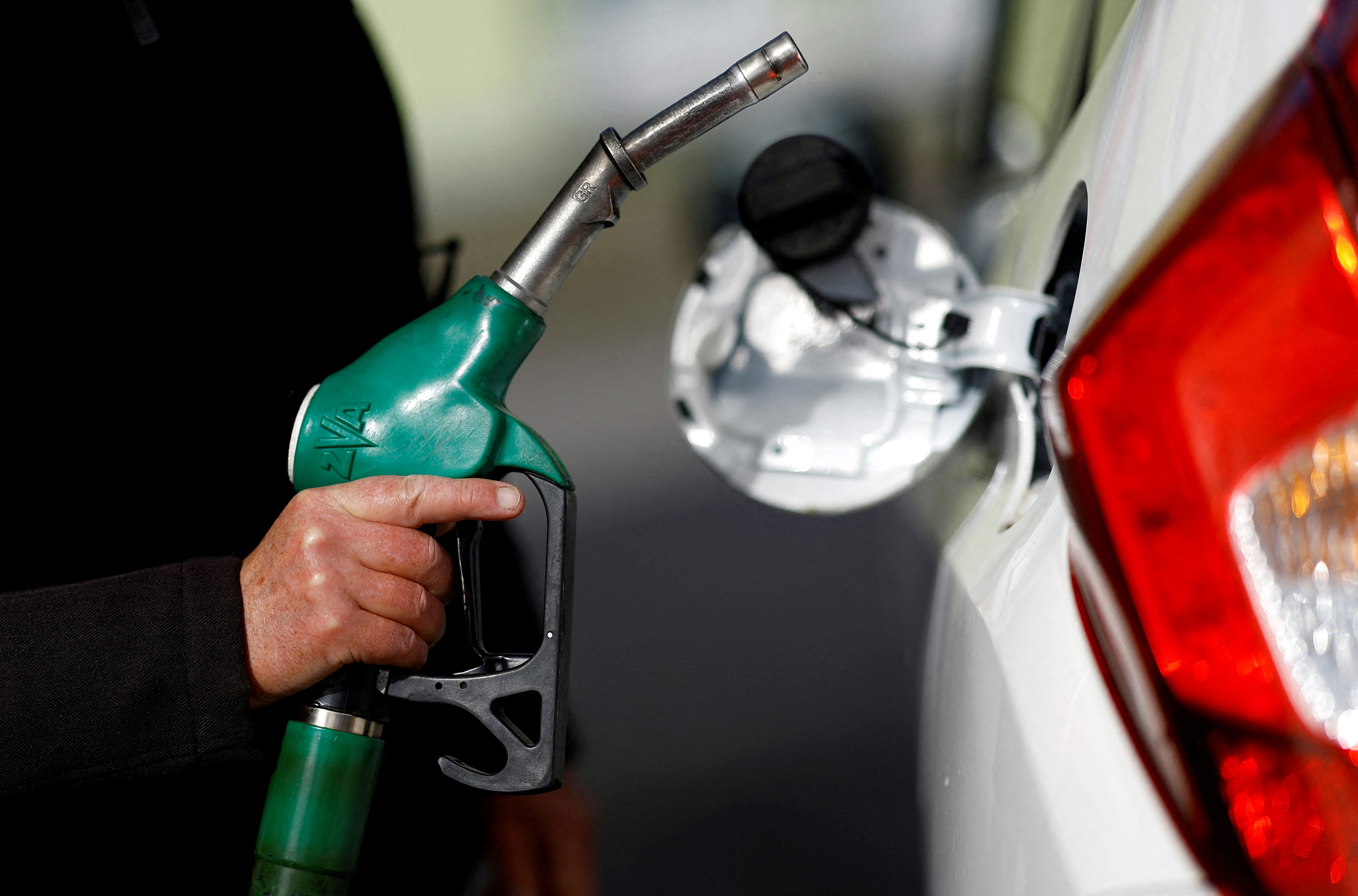 A man holds a fuel nozzle at a petrol station in Reze