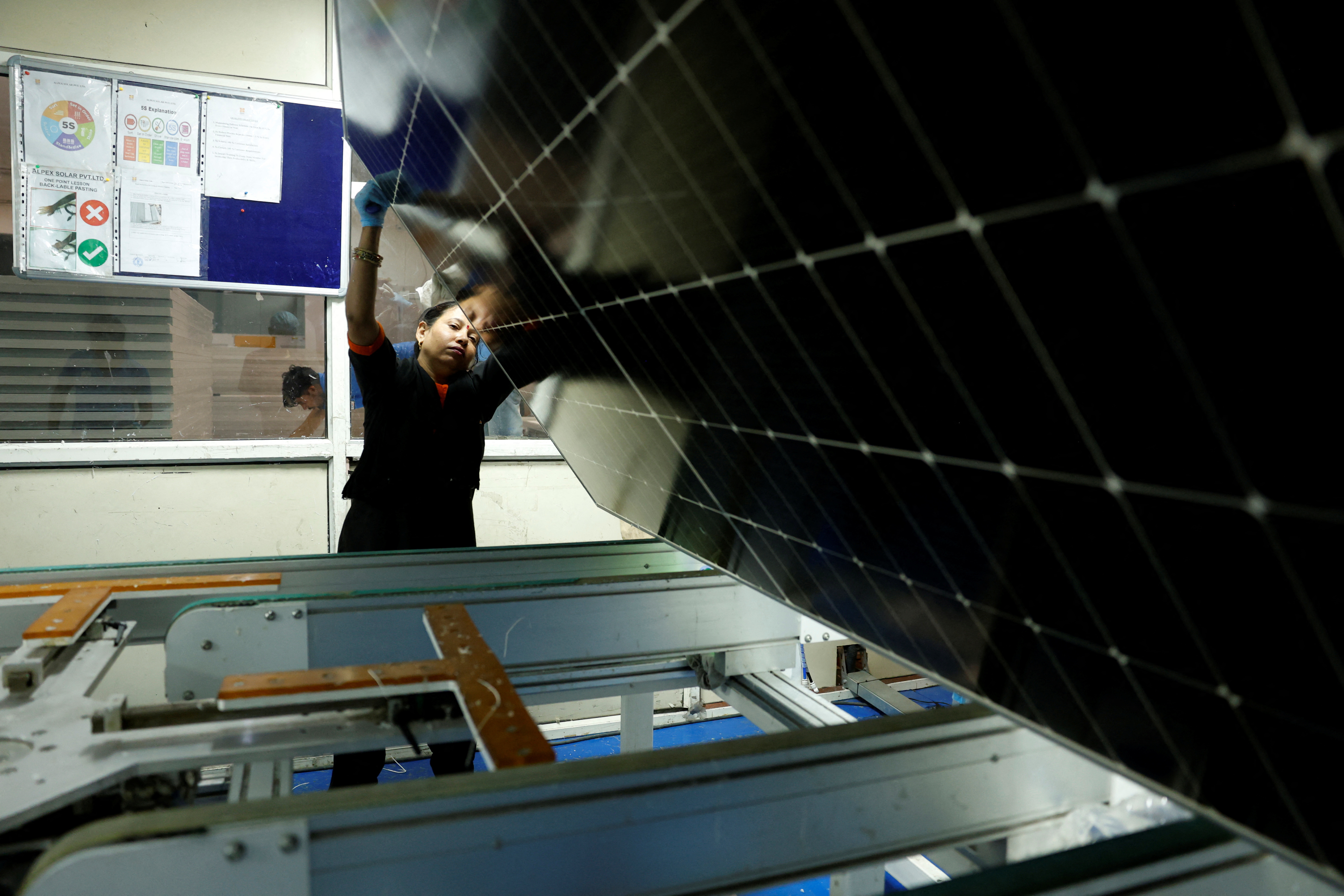 A female technician works on the assembly line at a solar panel manufacturing hub, in Greater Noida