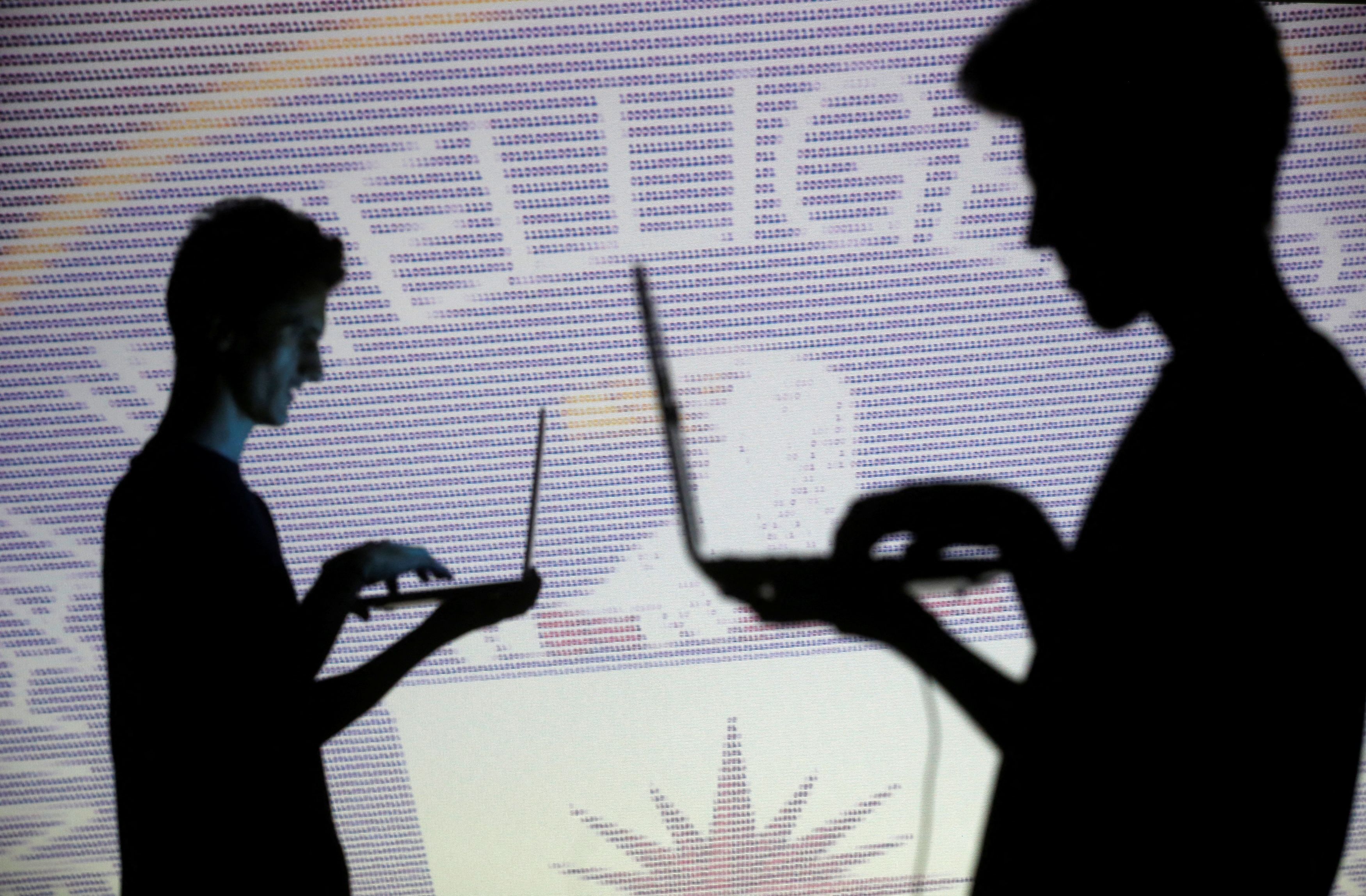 People pose with laptops in front of projection of  binary code and CIA emblem in this picture illustration taken in Zenica