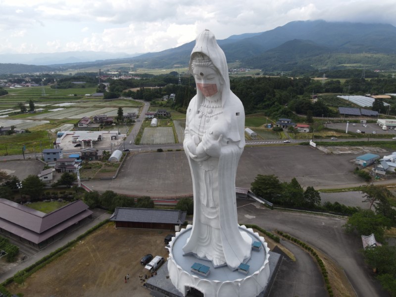 A drone picture shows a mask placed on a 57-metre-high statue of Buddhist goddess Kannon, to pray for the end of the coronavirus disease (COVID-19) pandemic at Houkokuji Aizu Betsuin temple in Aizuwakamatsu, Fukushima Prefecture, Japan in this handout photo taken on June 15 2021. OISO ALL SUPPORT/Handout via REUTERS 