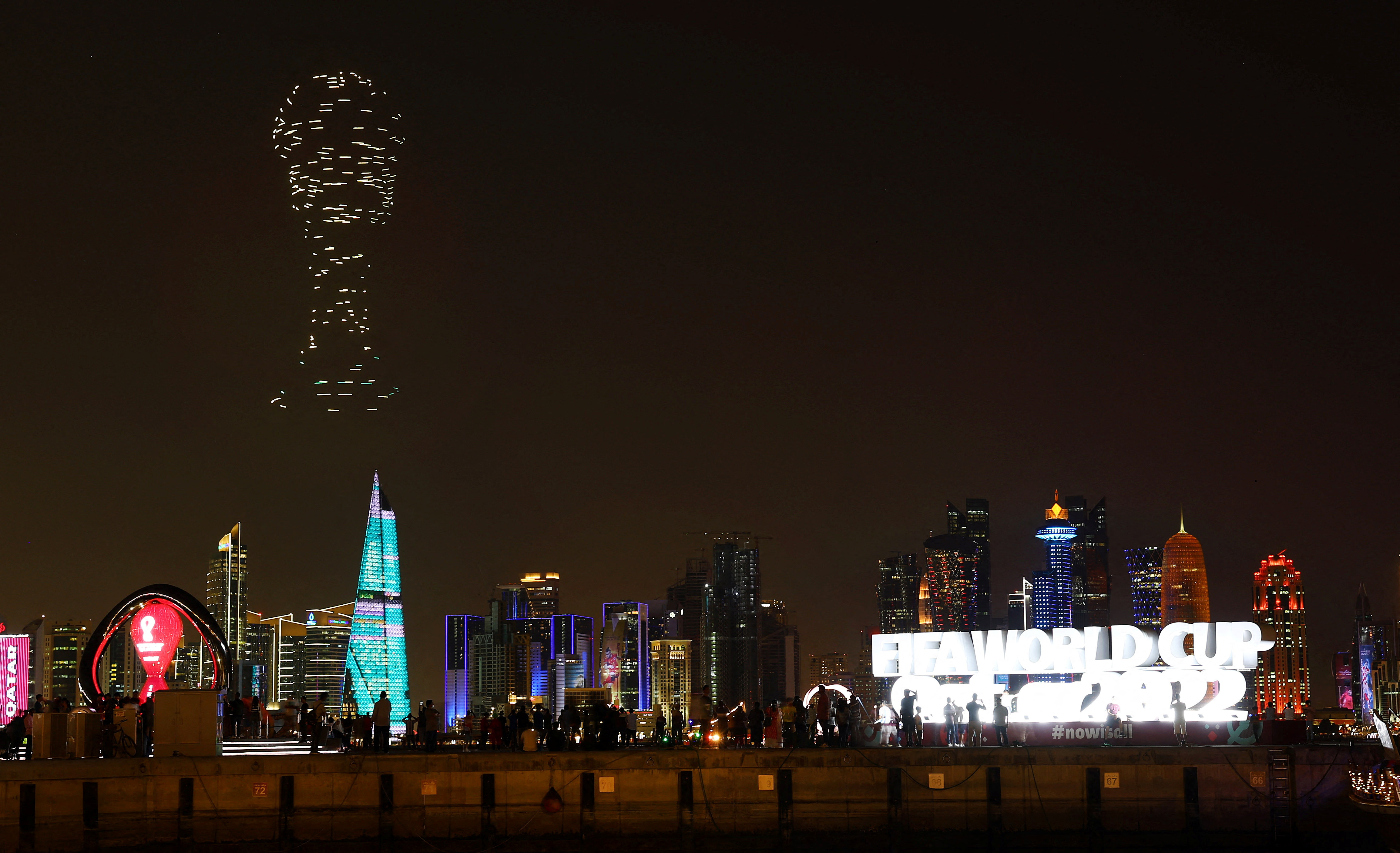 A drone show with the World Cup trophy on display is seen above the skyline of Doha